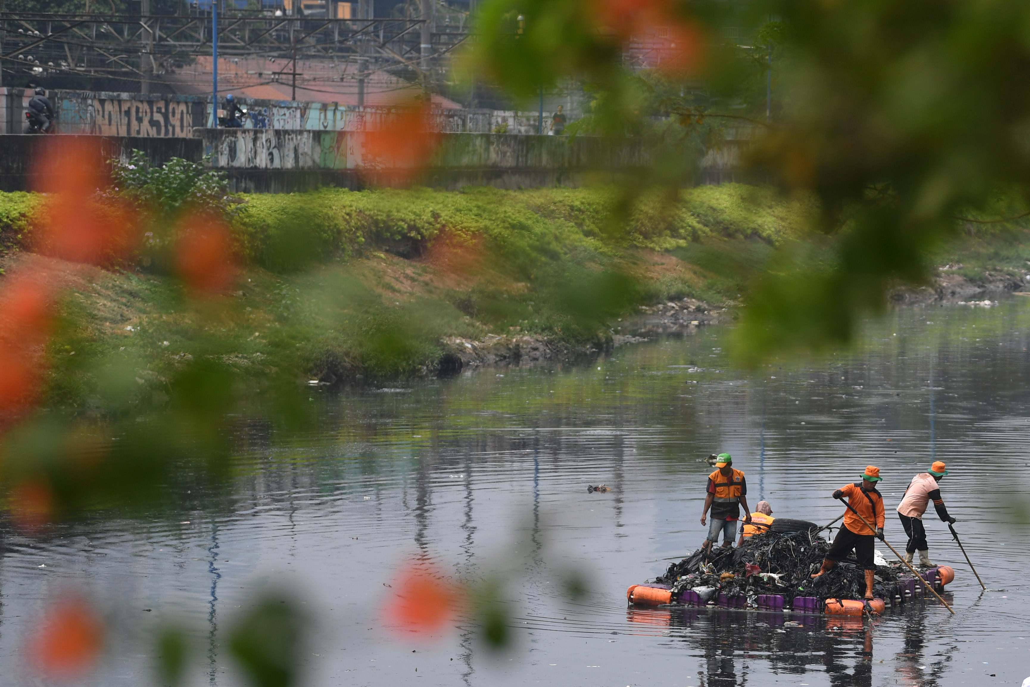 Petugas kebersihan mengambil sampah di aliran sungai Kanal Bajir Barat, Tanah Abang, Jakarta