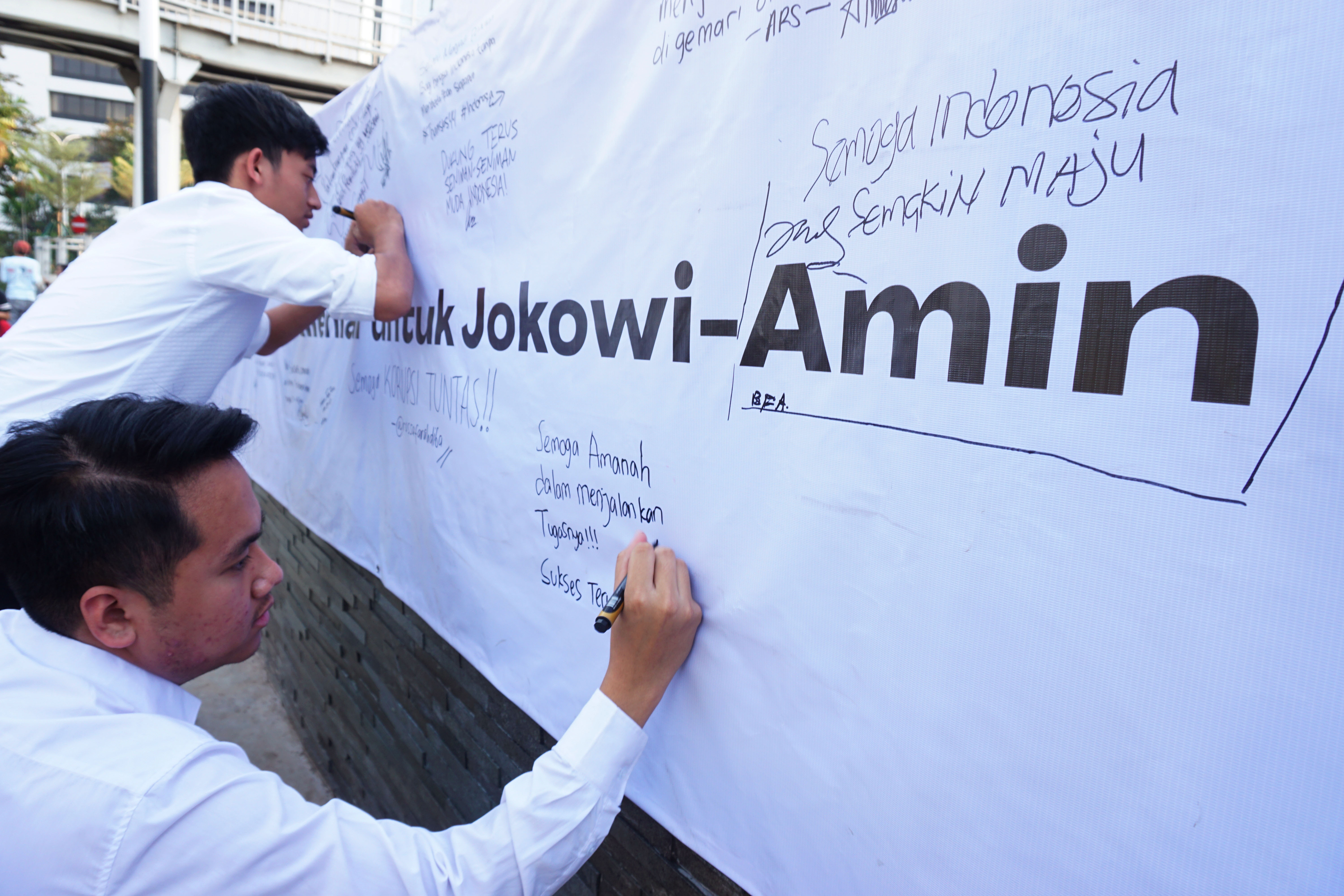 Peserta Young penting Indonesia menuliskan harapan terhadap Joko Widodo-Ma'ruf Amin saat aksi damai di Jakarta, Sabtu (19/10)