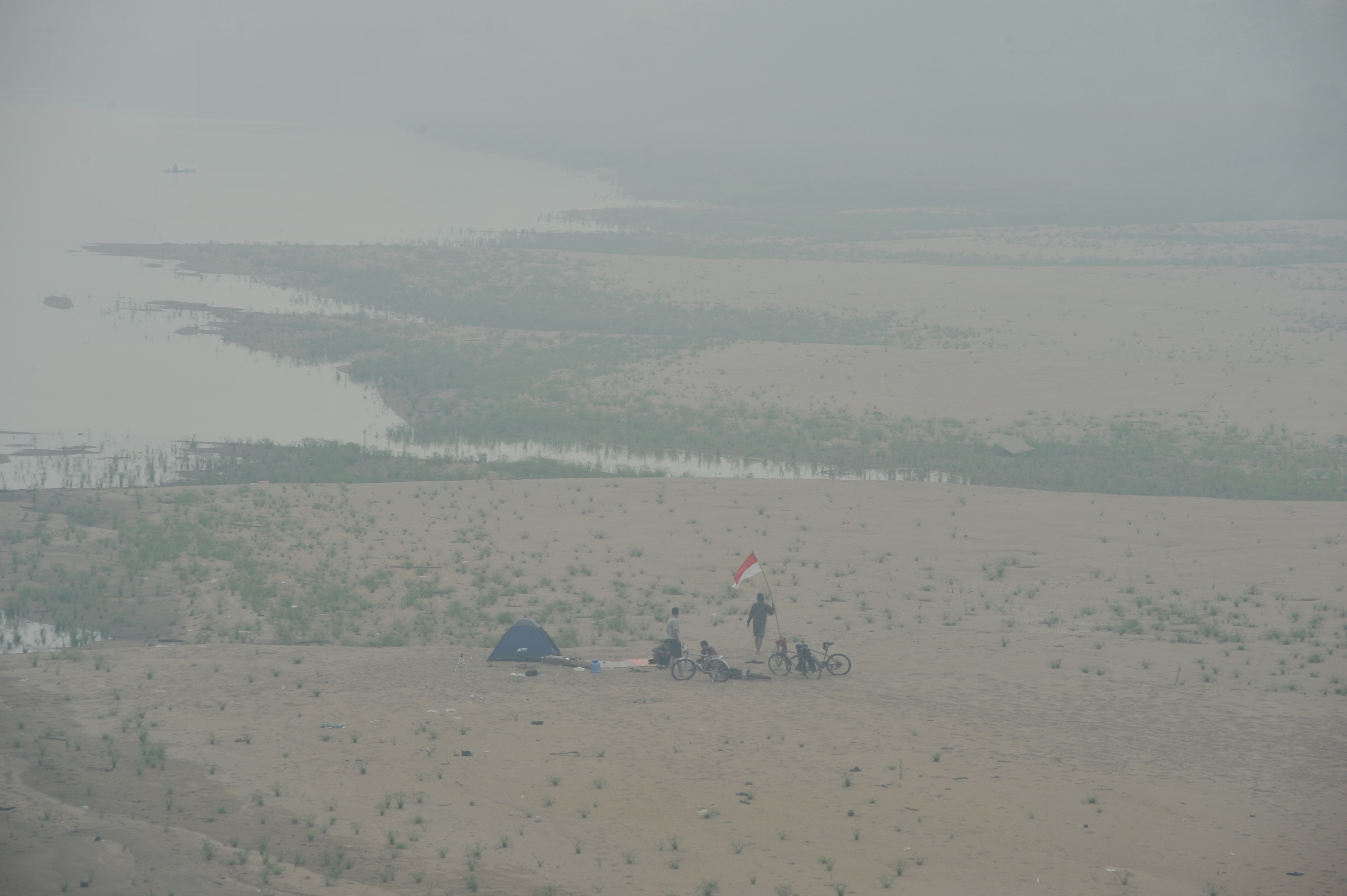 Warga berada di tepi Sungai Batanghari yang diselimuti kabut asap kebakaran hutan dan lahan (karhutla), Jambi, Selasa (15/10).