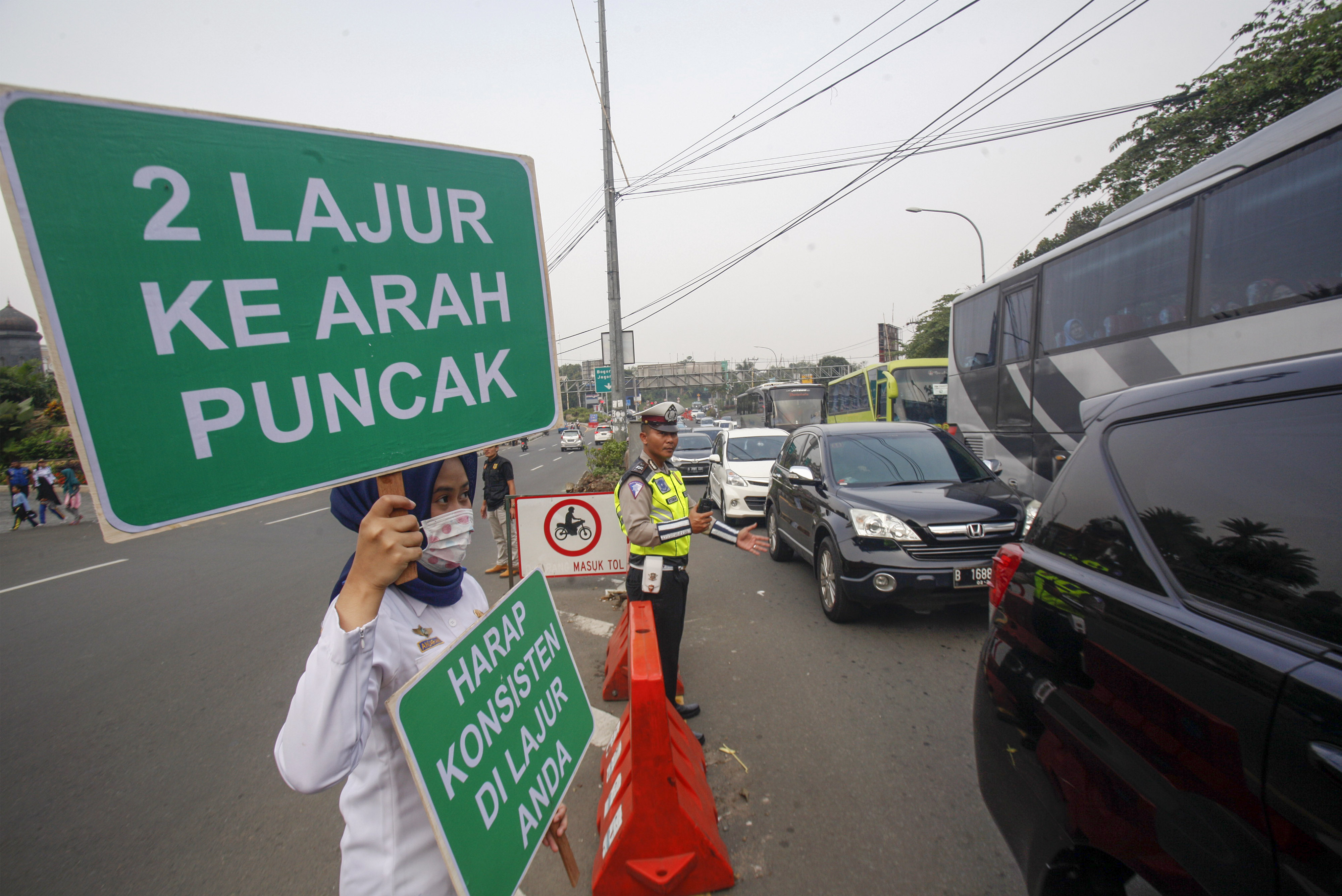 Petugas BPTJ membentangkan papan informasi sosialisasi sistem kanalisasi di Jalur Puncak, Bogor, Jawa Barat, Minggu (27/10)