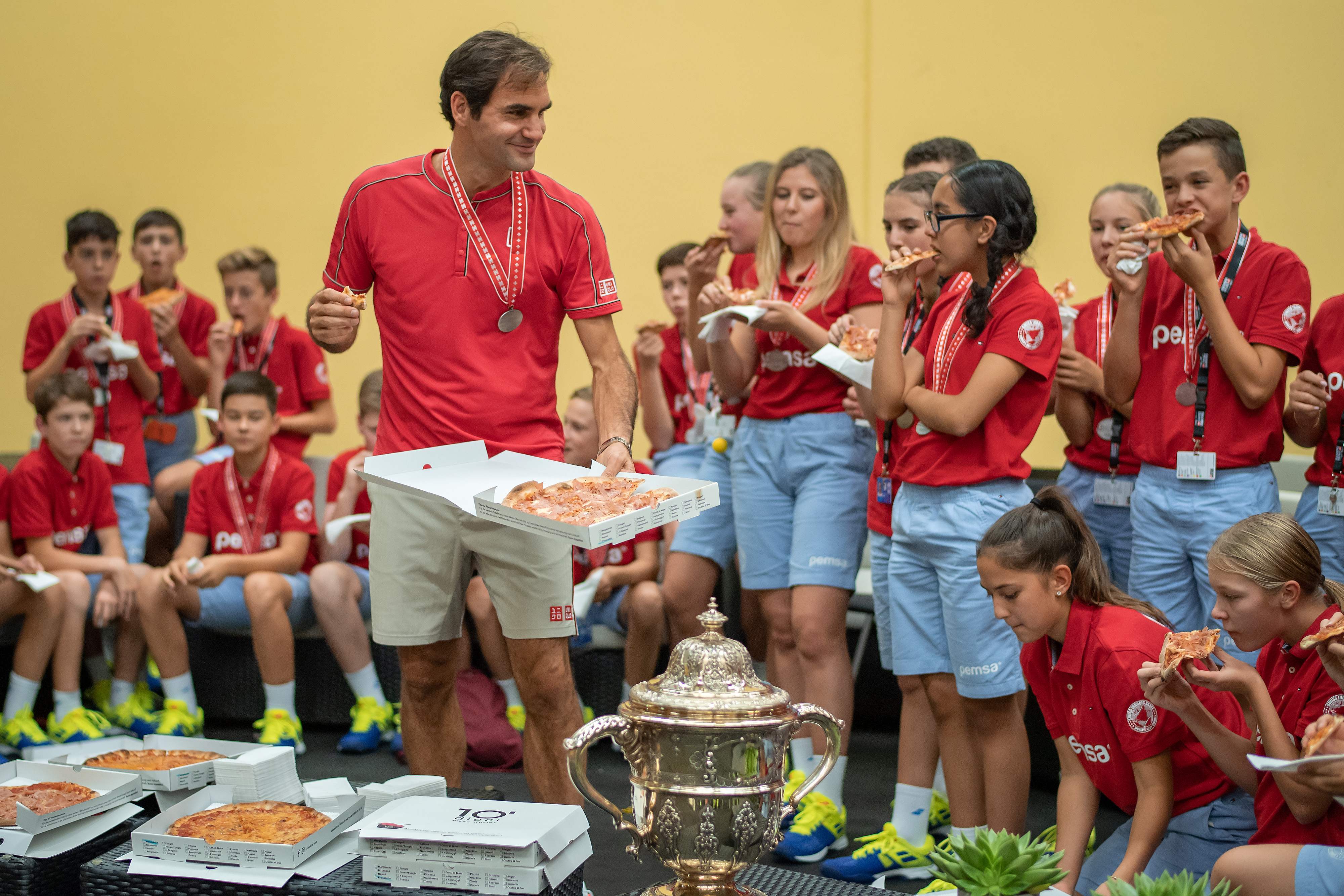 Roger Federer (tengah) makan piza bersama para ballkids usai menjadi juara ATP di Basel.