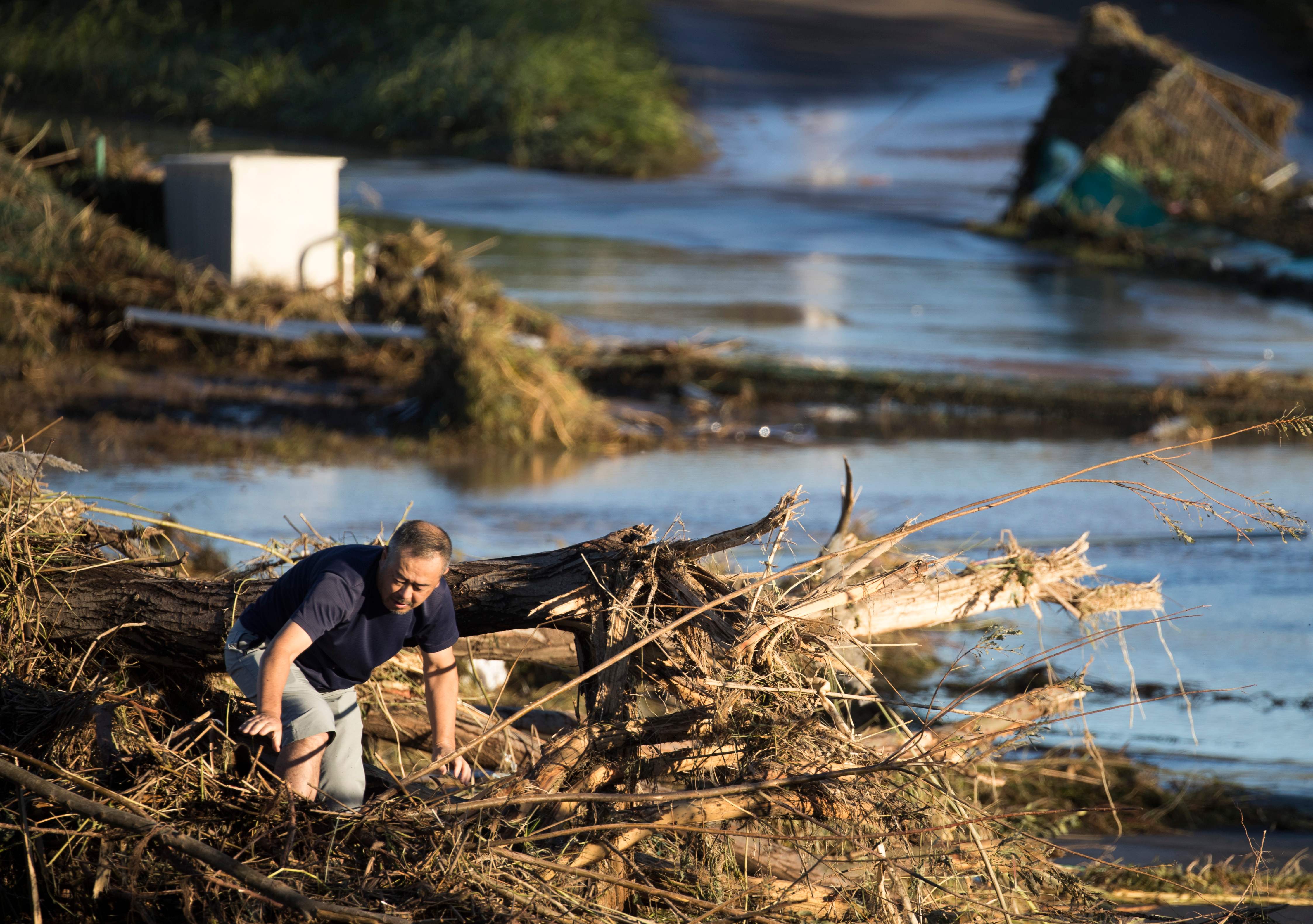 Seorang laki-laki berjalan di antara sampah bersamaan bajir yang melanda wilayah Jepang