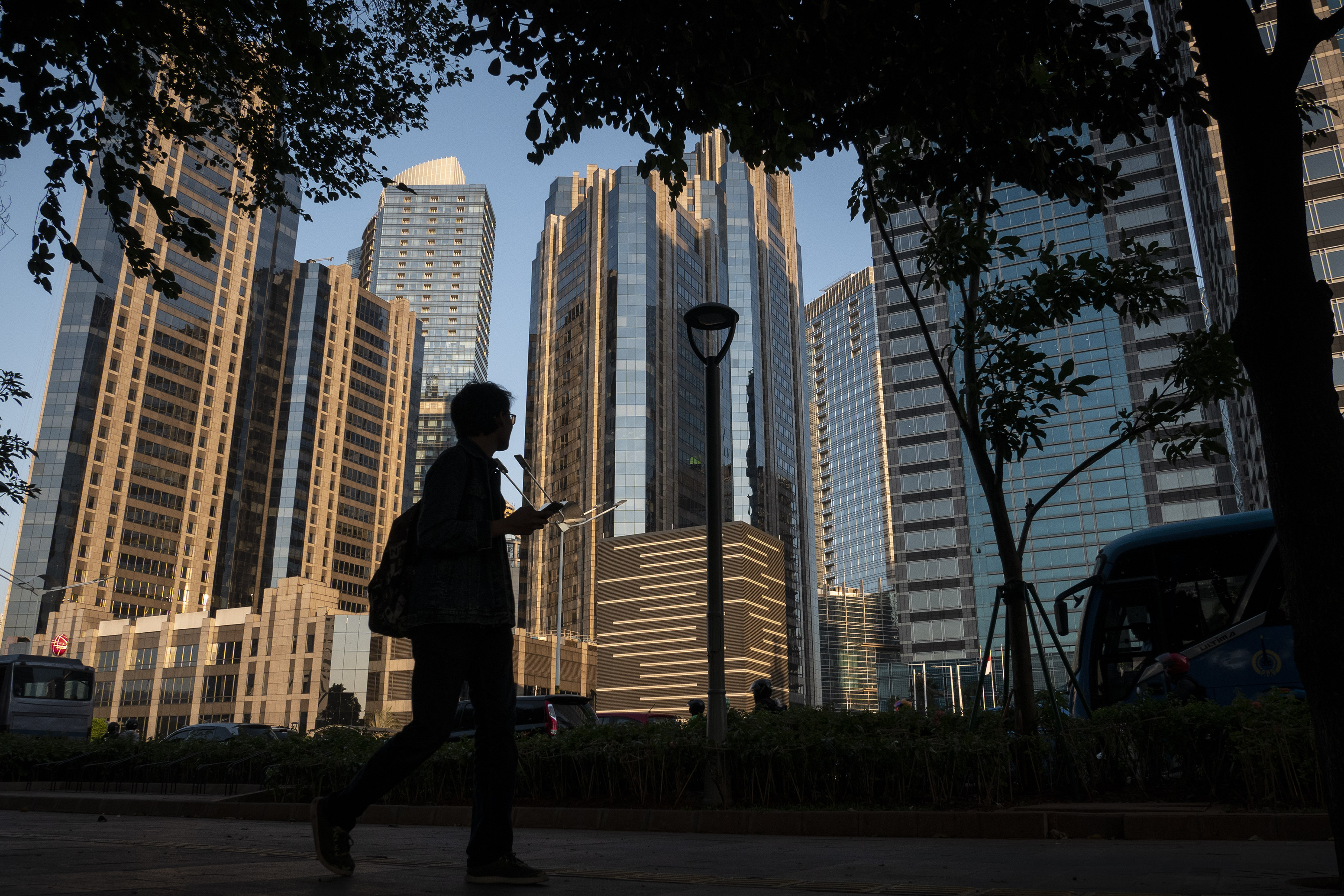 Seorang warga beraktivitas dengan latar belakang gedung perkantoran di kawasan Jakarta Selatan, Rabu (11/9/2019).