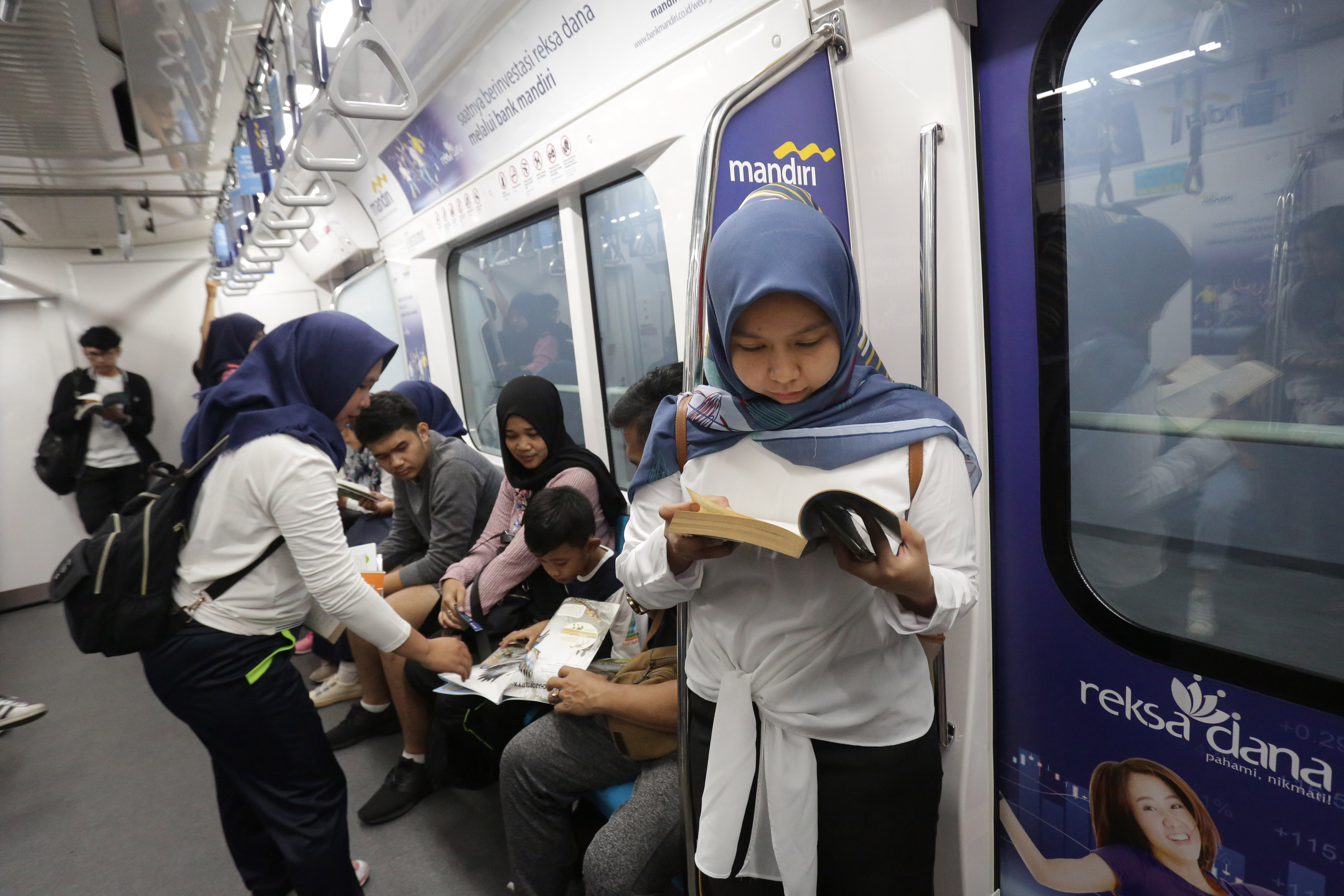 Penumpang MRT mengisi waktu perjalanan dengan membaca buku.