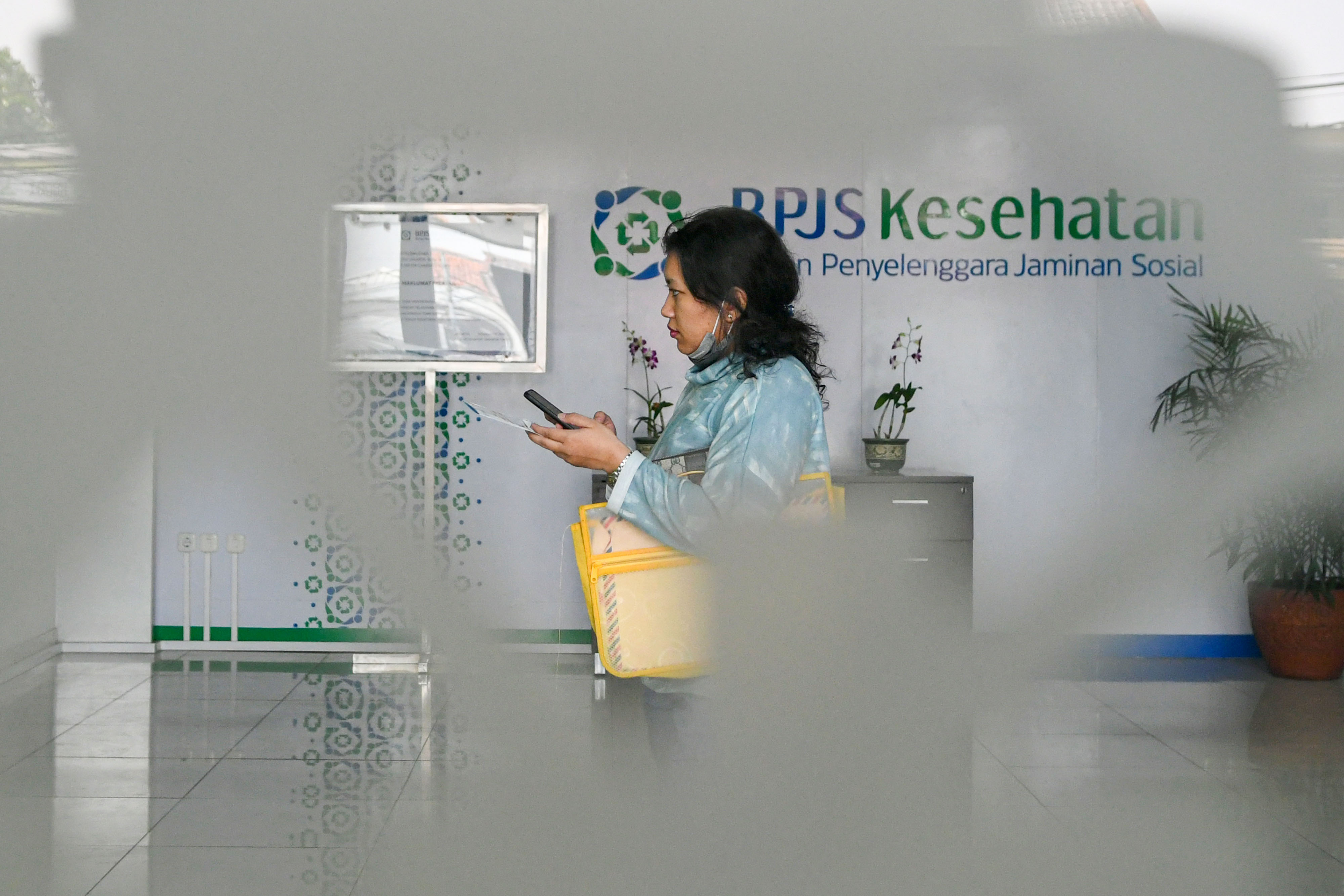 Warga berjalan di lobi kantor Badan Penyelenggara Jaminan Sosial (BPJS) Kesehatan Jakarta Timur, di Jakarta, Rabu (30/10). 