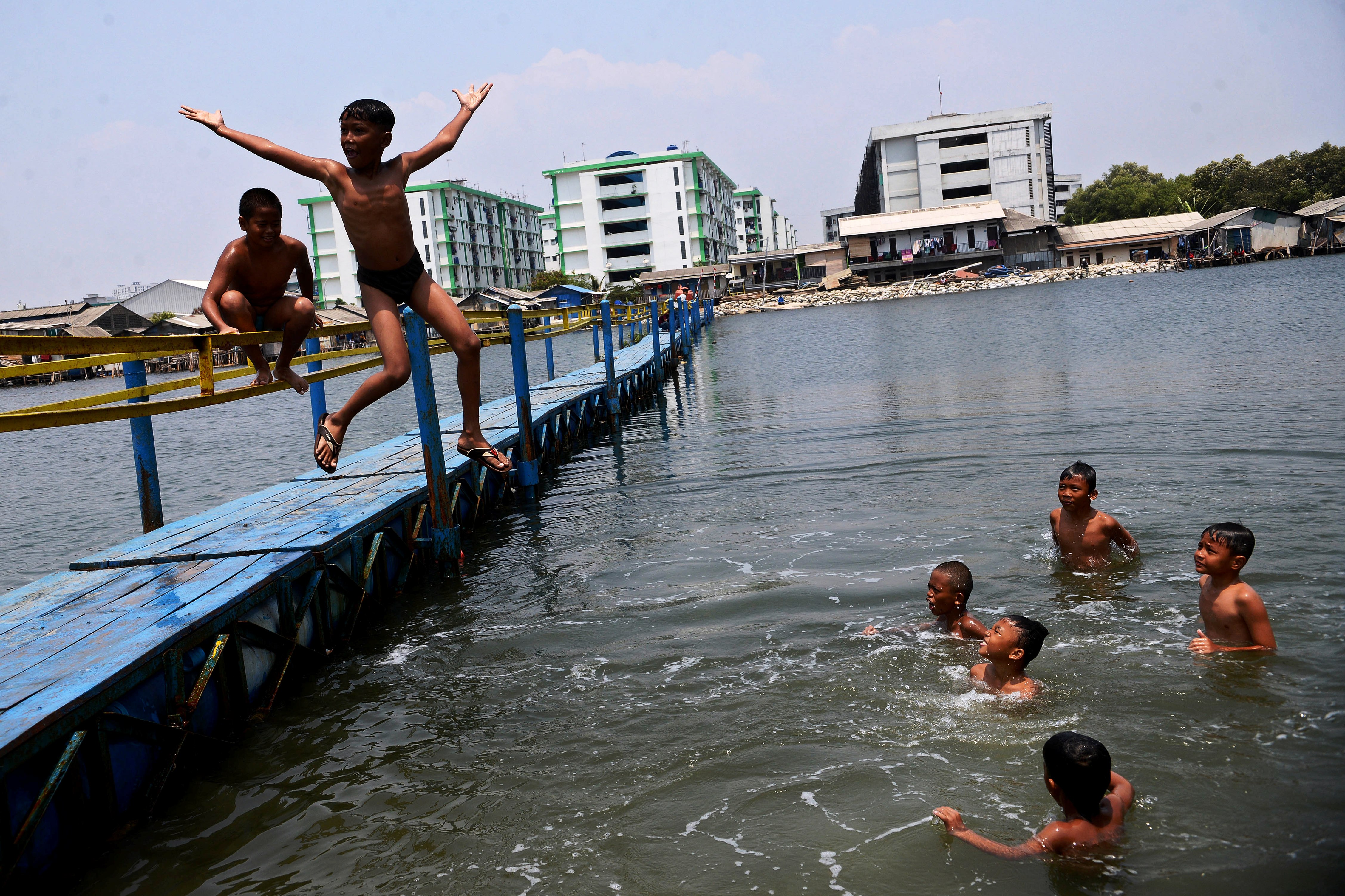 Anak-anak bermain air di jembatan apung kawasan tanggul Muara Baru, Penjaringan, Jakarta Utara, Minggu (1/9).