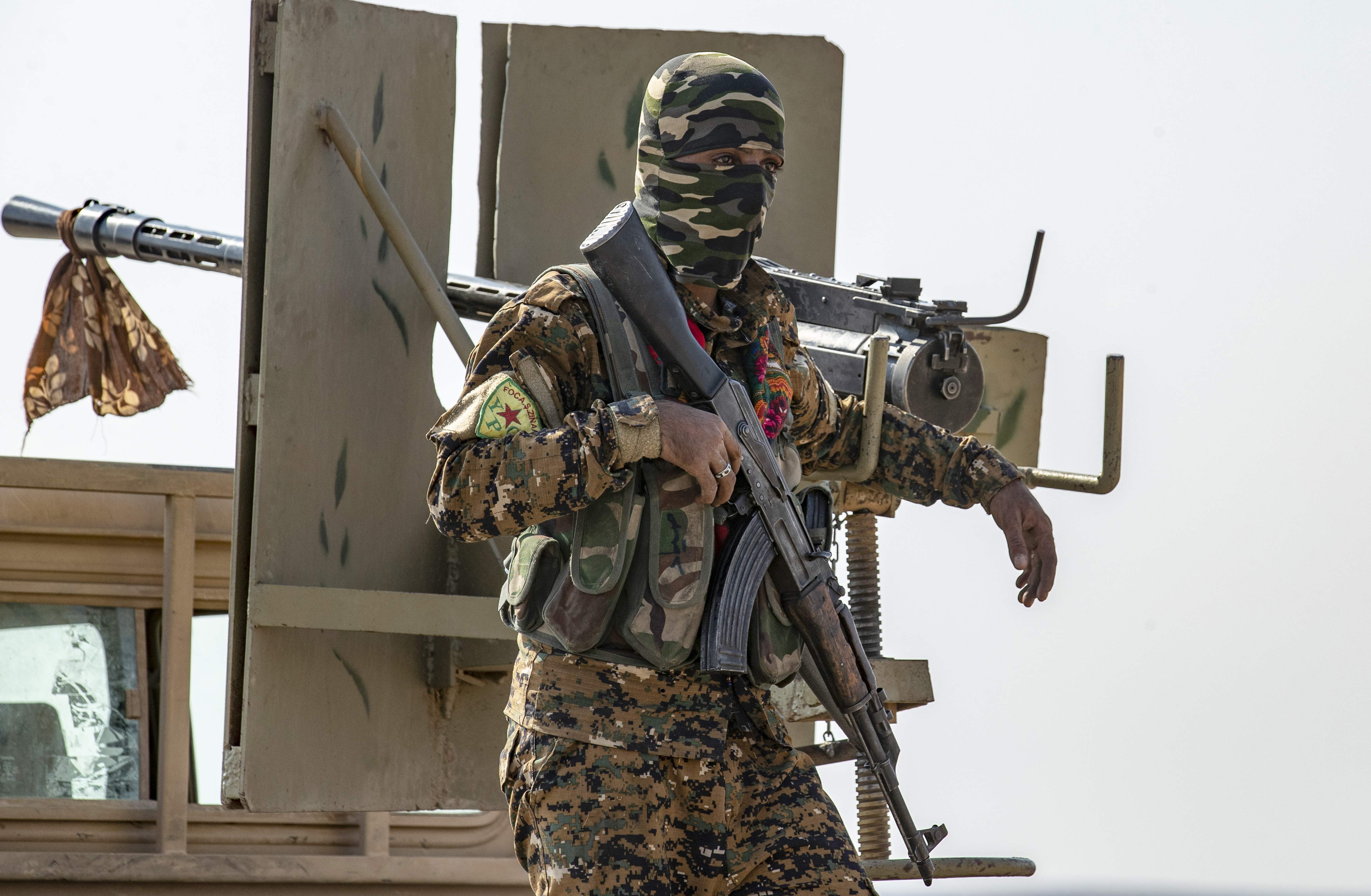 Seorang personel SDF berdiri di atas sebuah kendaraan militer