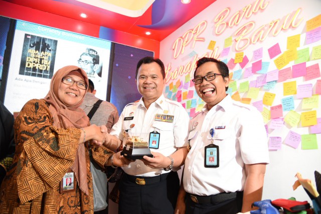 Kasubag Penerangan Humas DPR RI Erna Agustina saat memberikan cinderamata pada pengunjung booth Humas Biro Pemberitaan Parlemen. 