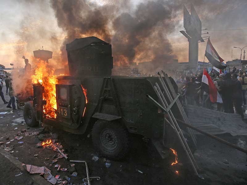 Sebuah kendaraan anti huru-hara Polisi Irak dibakar demonstran di Tayeran Square, Baghdad, Jumat (3/10/2019)