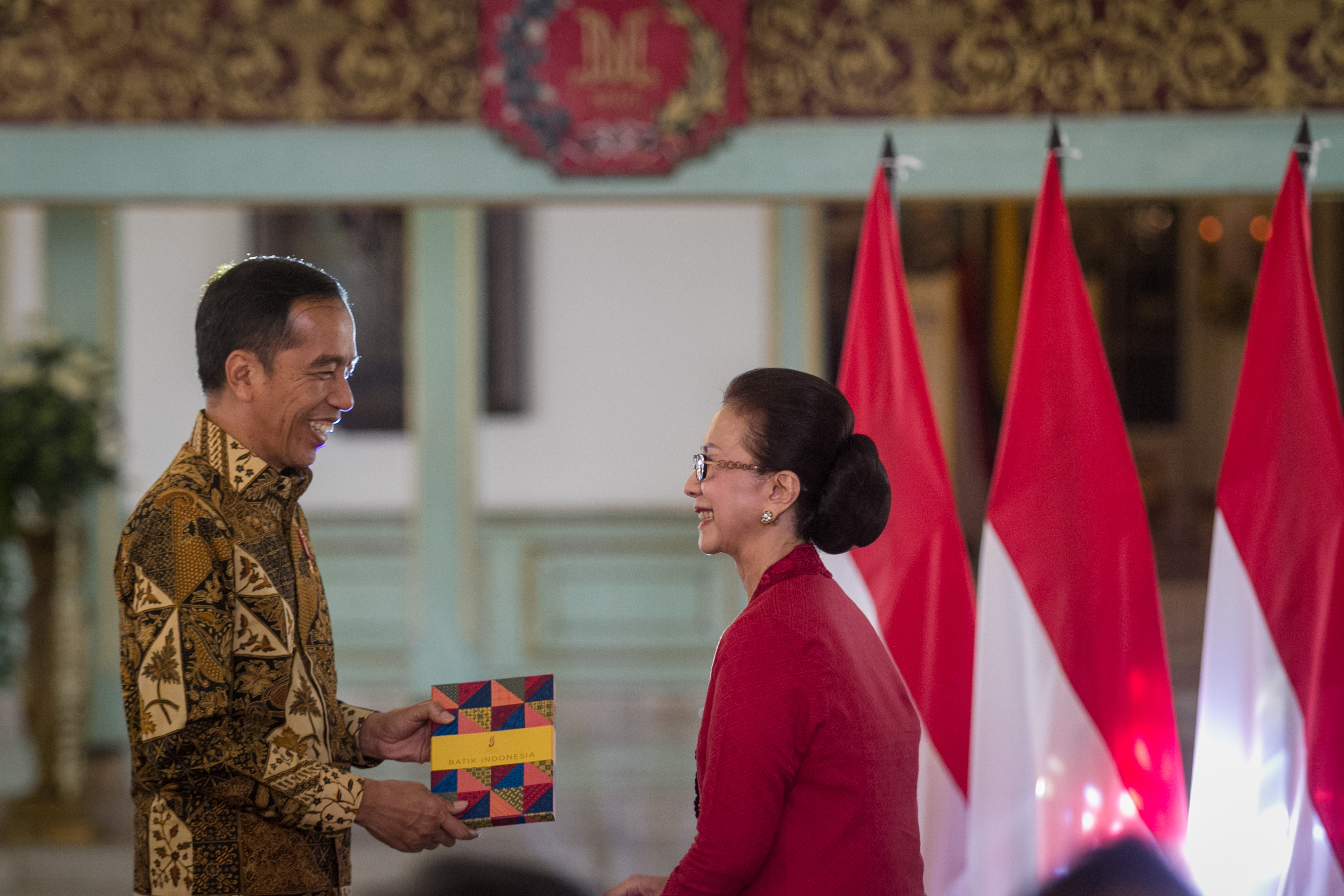 Presiden Joko Widodo (kiri) menerima kenang-kenangan buku Batik Indonesia dari Ketua Yayasan Batik Indonesia (YBI) Jultin Ginandjar (kanan)