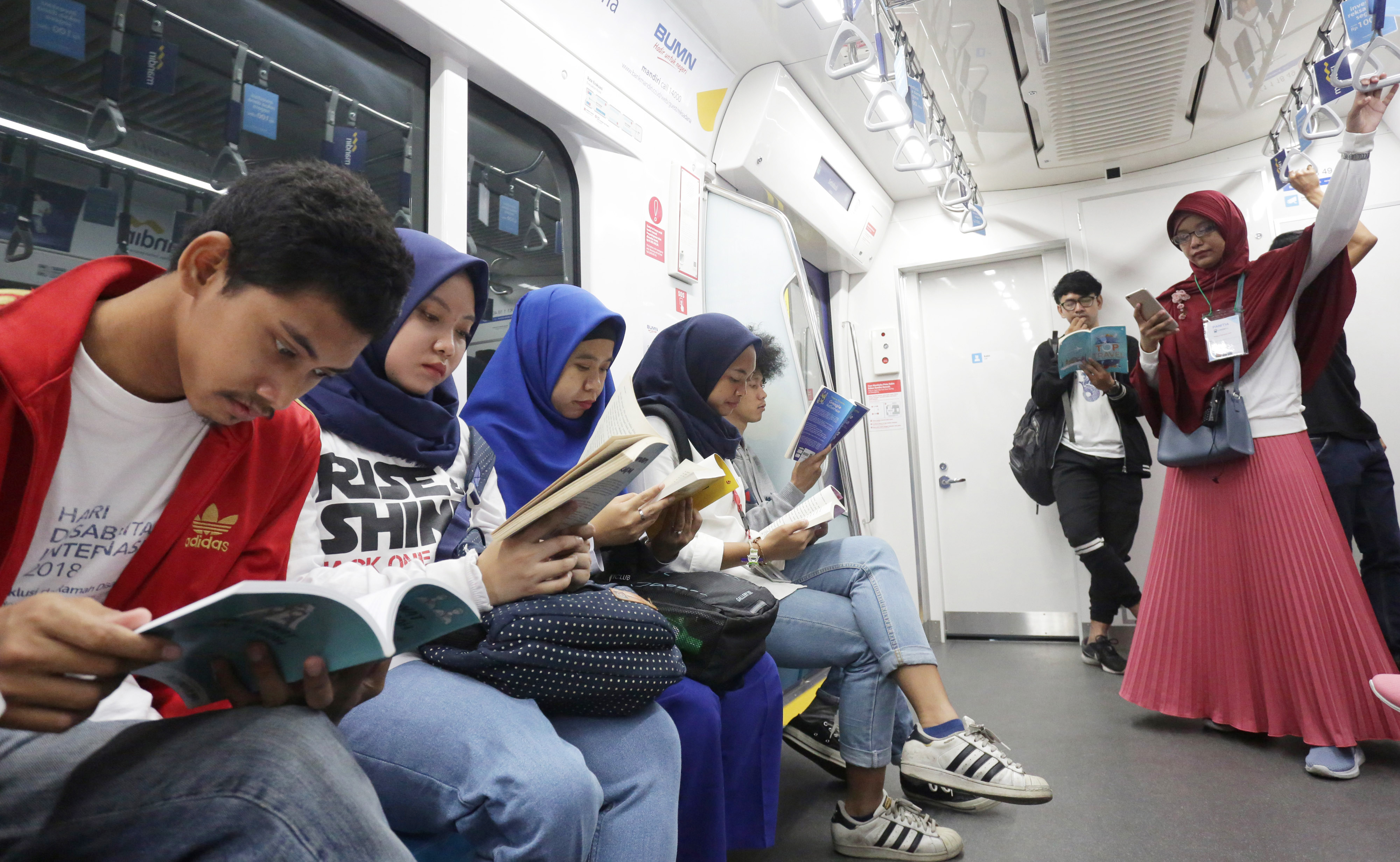 Penumpang MRT mengisi waktu perjalanan dengan membaca buku yang tersedia di pojok buku Stasiun MRT.