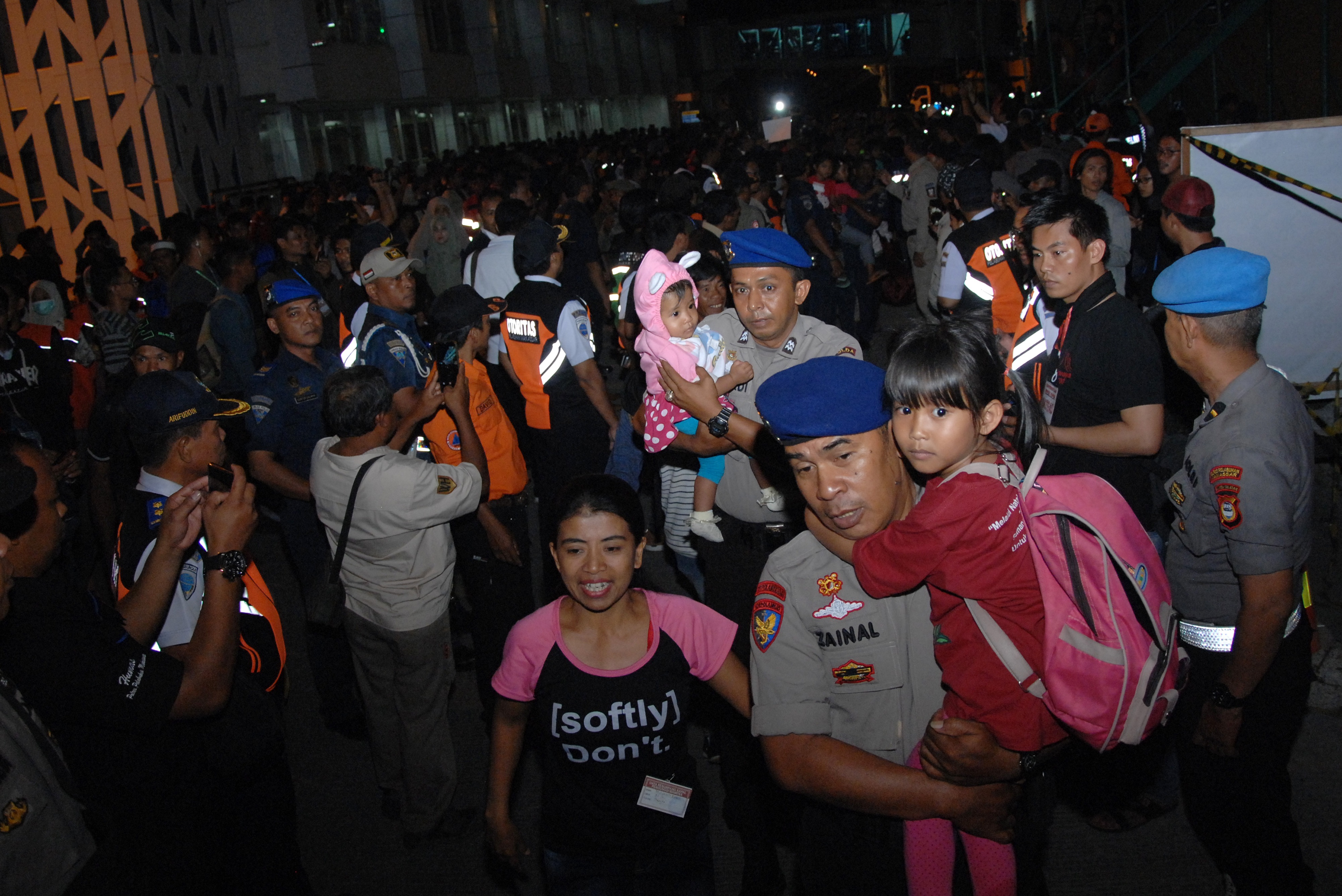 Anggota polisi menggendong anak-anak pengungsi kerusuhan Wamena seusai turun dari KM Sinabung setibanya di Pelabuhan Sukarno Hatta, Makassar