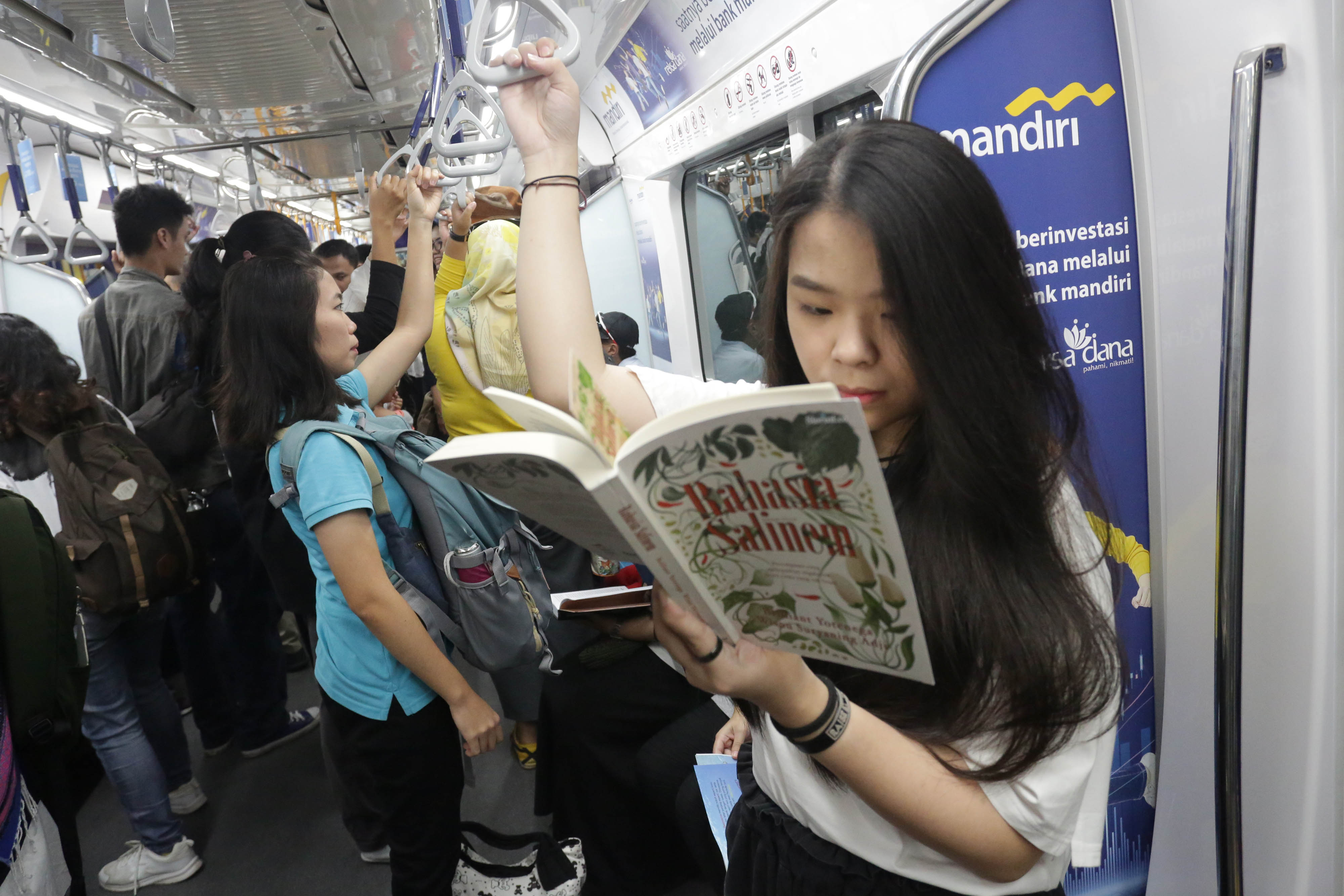 Penumpang MRT mengisi waktu perjalanan dengan membaca buku yang tersedia di pojok buku Stasiun MRT Bundaran HI, Jakarta, Minggu (8/9)