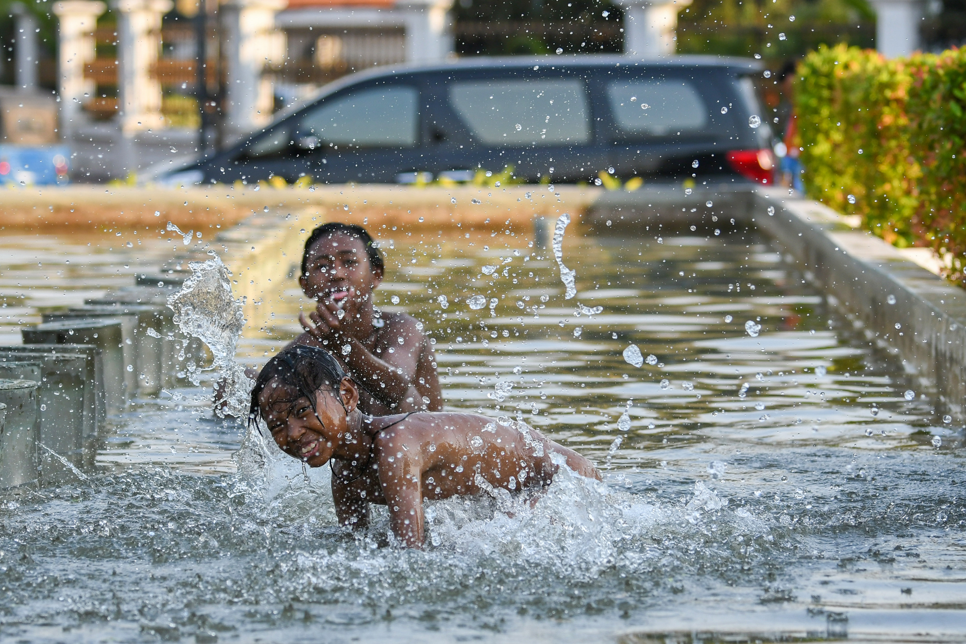 Dua bocah bermain di kolam air mancur di atas sungai Ciliwung, Pasar Baru, Jakarta.