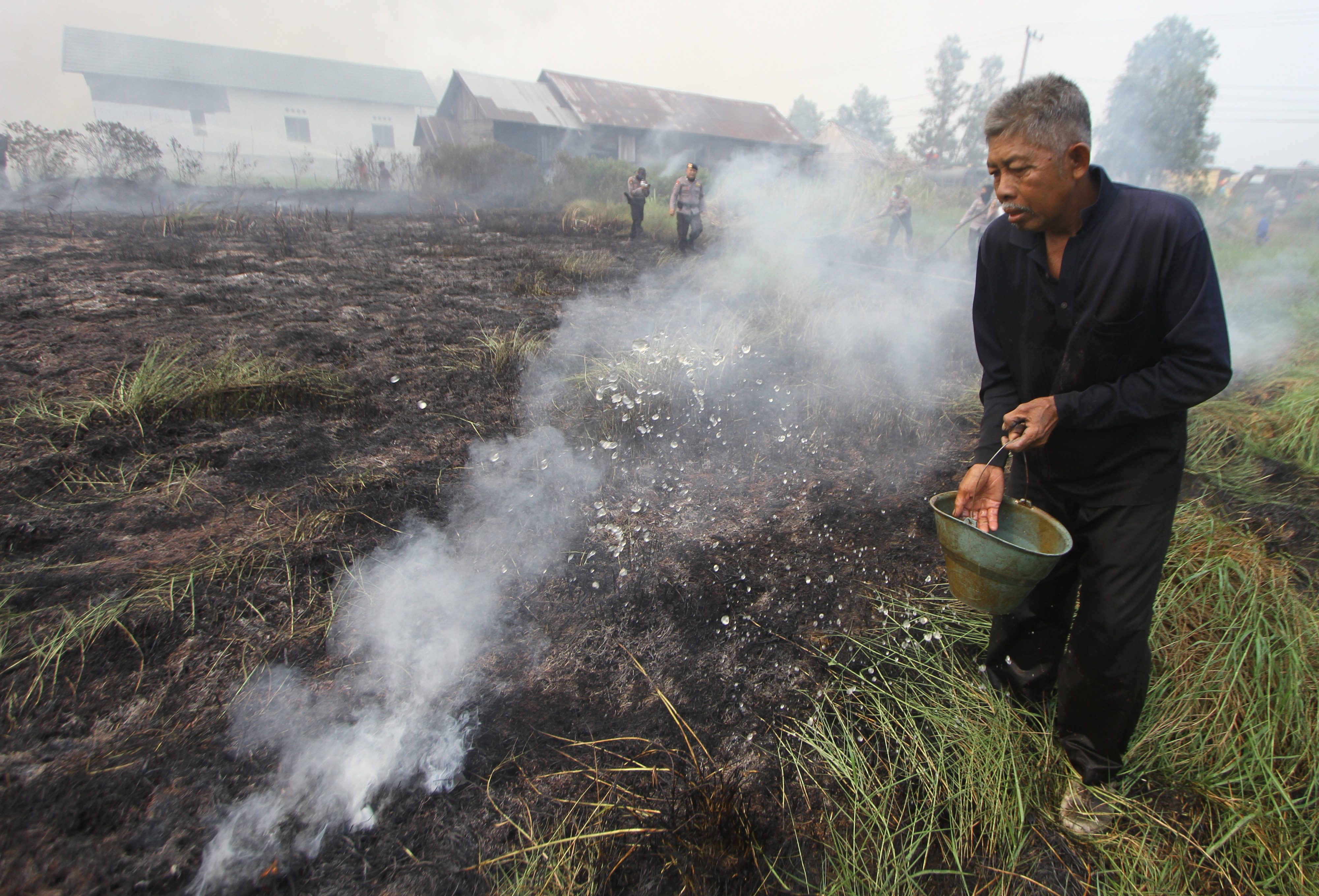 Warga membasahi lahan gambut yang terbakar di Desa Pengayuan, Kecamatan Liang Anggang, Banjarbaru, Kalsel. 