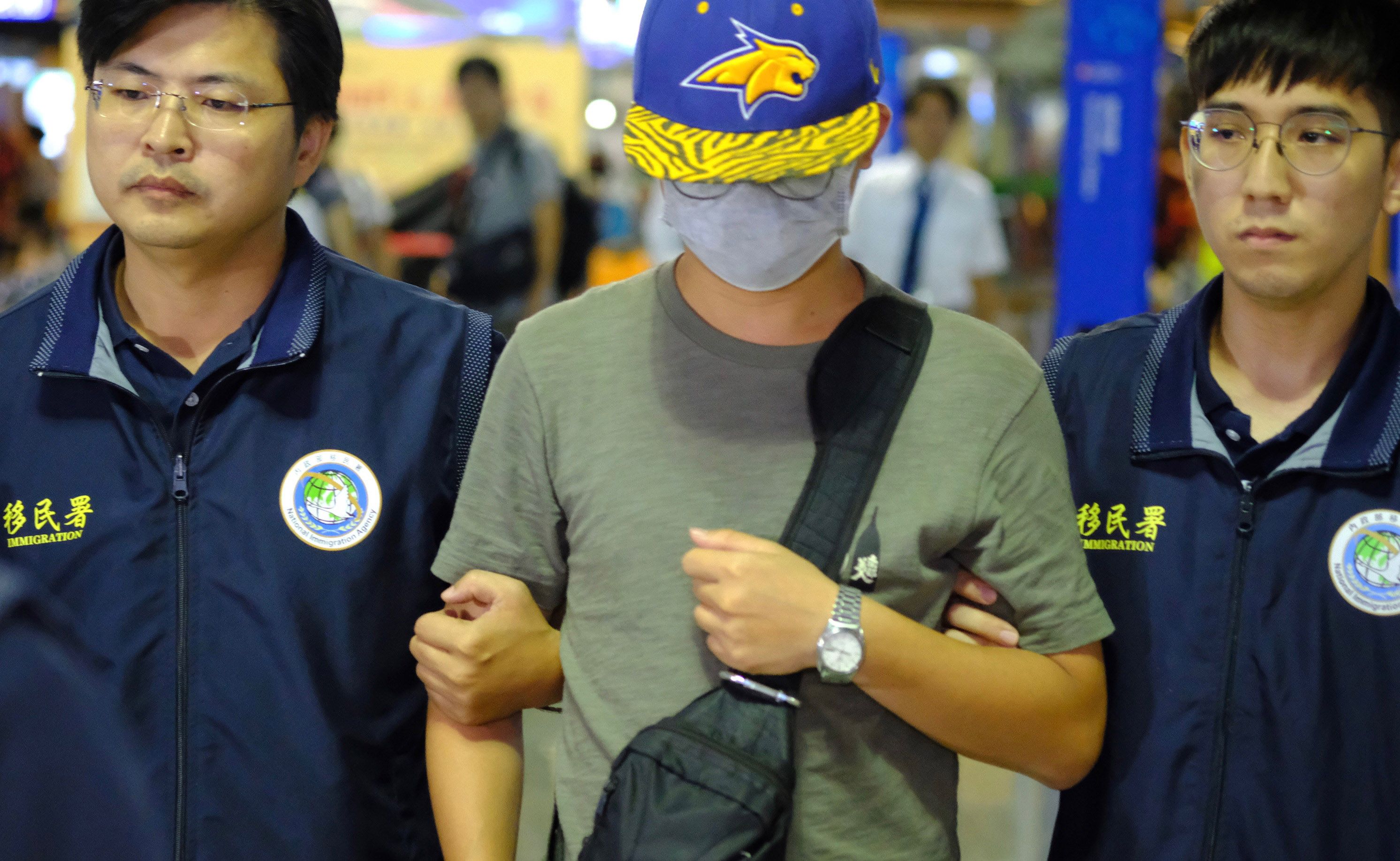 Turis Tiongkok Li Shaodong (tengah) dikawal petugas imigrasi Taiwan di Bandara Taoyuan untuk dideportasi.