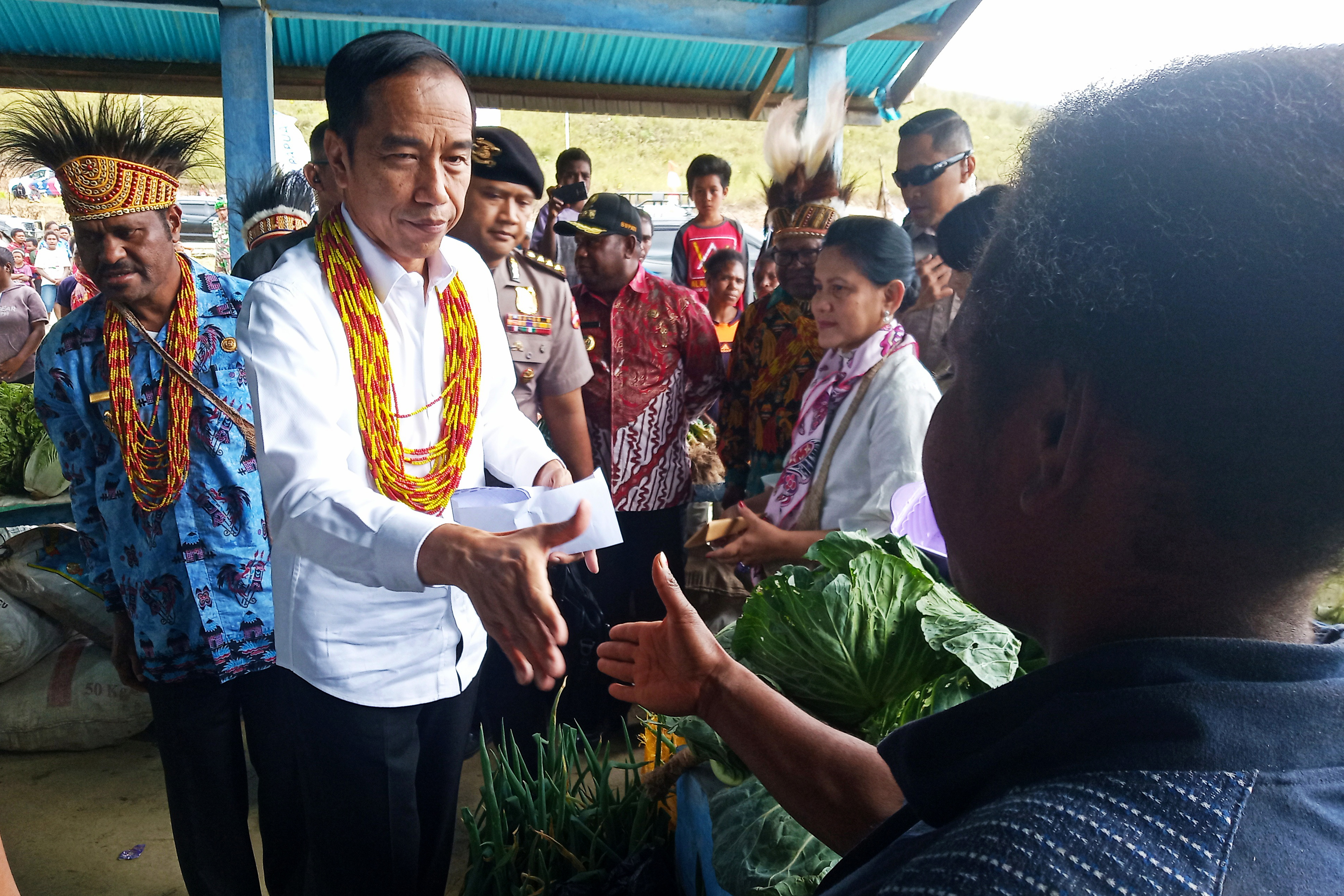 Presiden Joko Widodo (kedua kiri) bersama Ibu Negara (ketiga kanan) menyapa warga saat meninjau pasar khusus Mama Papua di Distrik Anggi