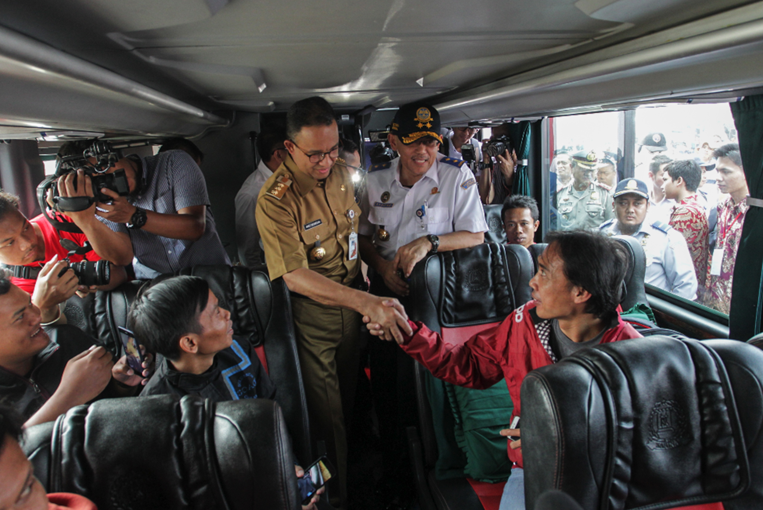 Gubernur DKI Jakarta Anies Baswedan (tengah) berbincang dengan sejumlah penumpang peserta mudik bersama di Monas.