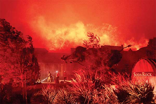 Petugas pemadam kebakaran berada di kilang anggur Soda Rock Winery yang terbakar di Healdsburg, California, AS, Minggu (27/10).