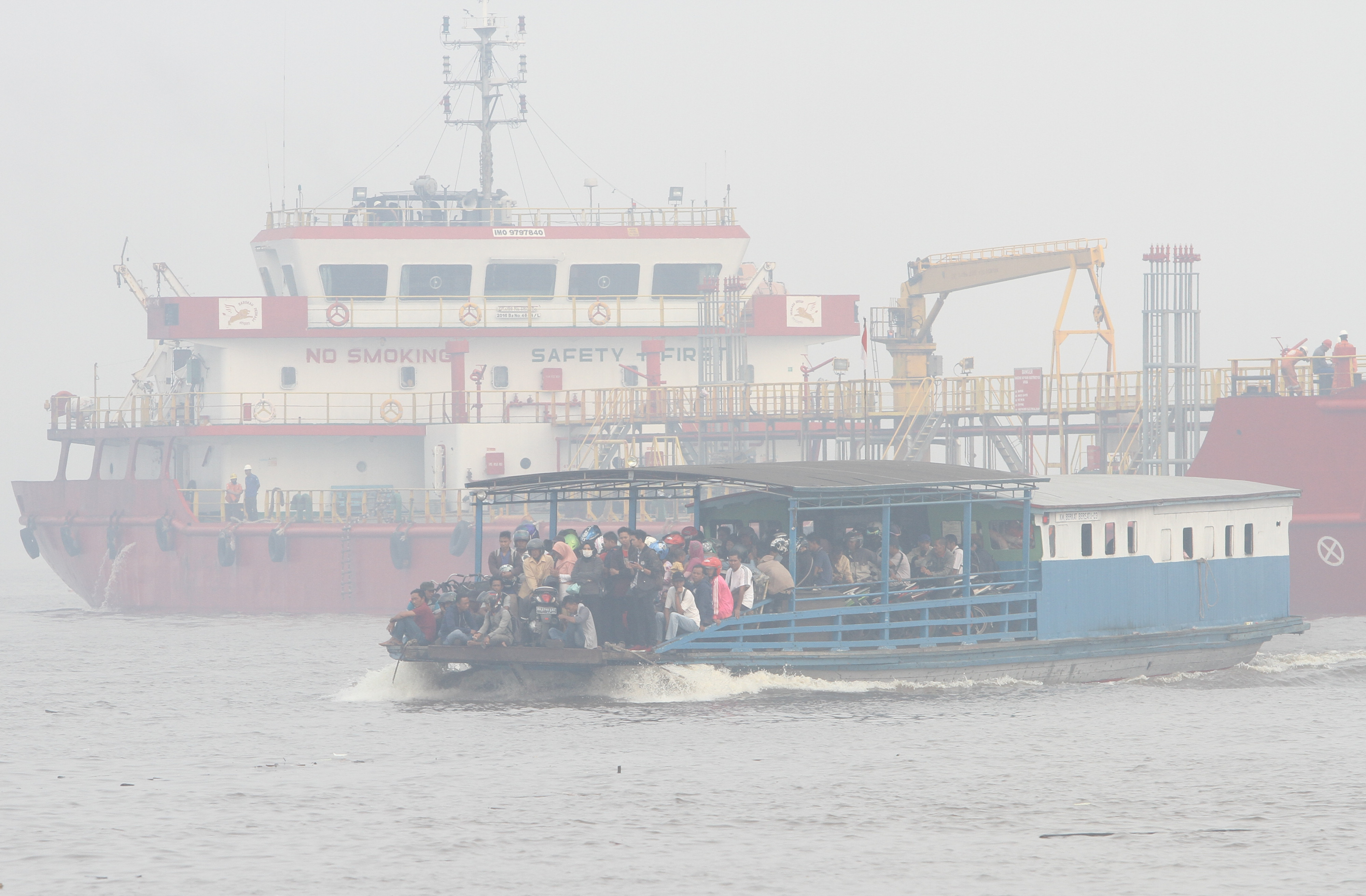 Kapal feri tradisional melintas di Sungai Barito yang diselimuti kabut asap di Banjarmasin, Kalimantan Selatan, Senin (14/10/2019)