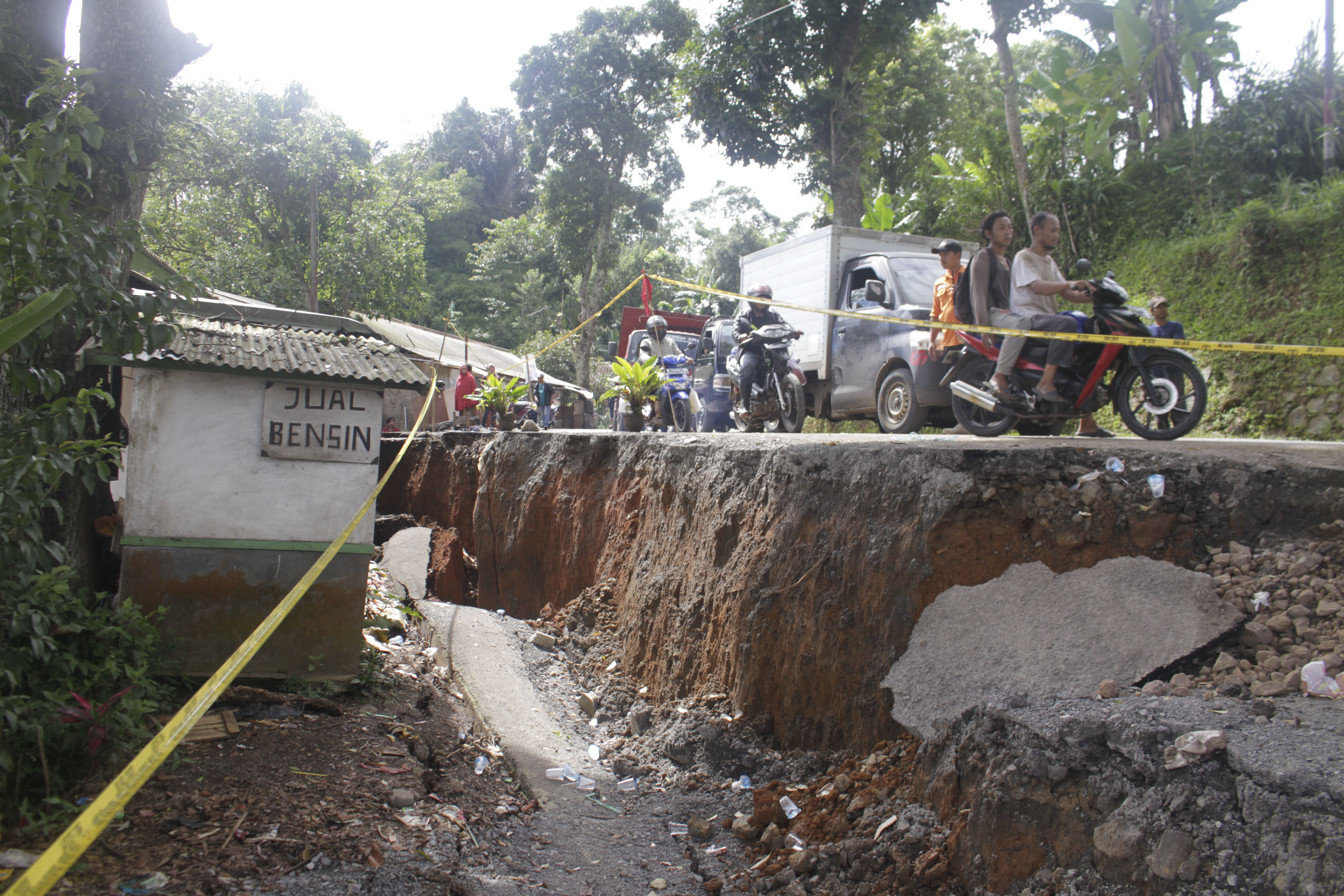 Sejumlah pengendara kendaraan bermotor melintasi jalan yang ambles di Jalan Sukabumi-Sagaranten, Kampung Gunungbatu