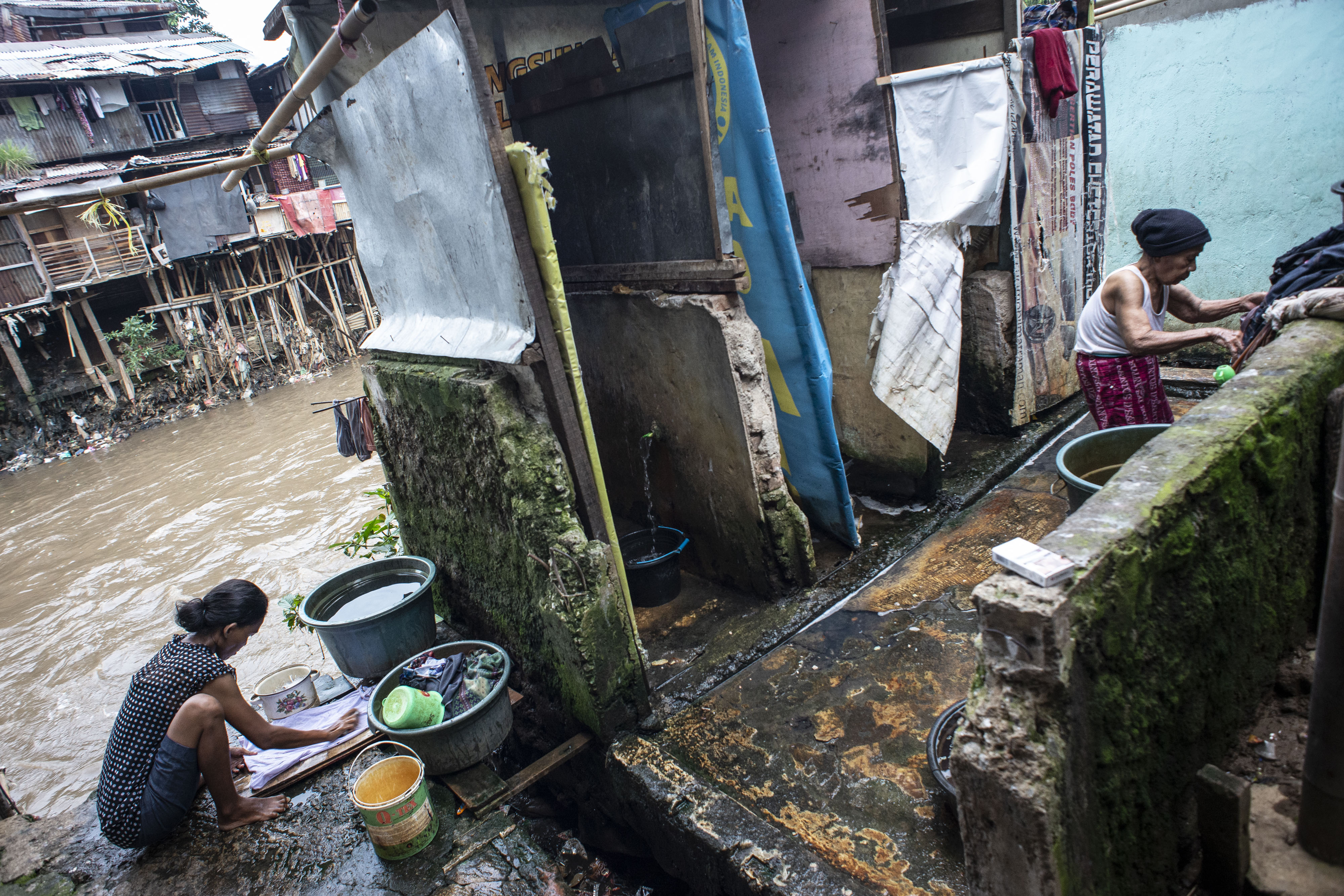 Warga mencuci pakaian di toilet umum yang dibangun di bantaran Sungai Ciliwung, Jakarta