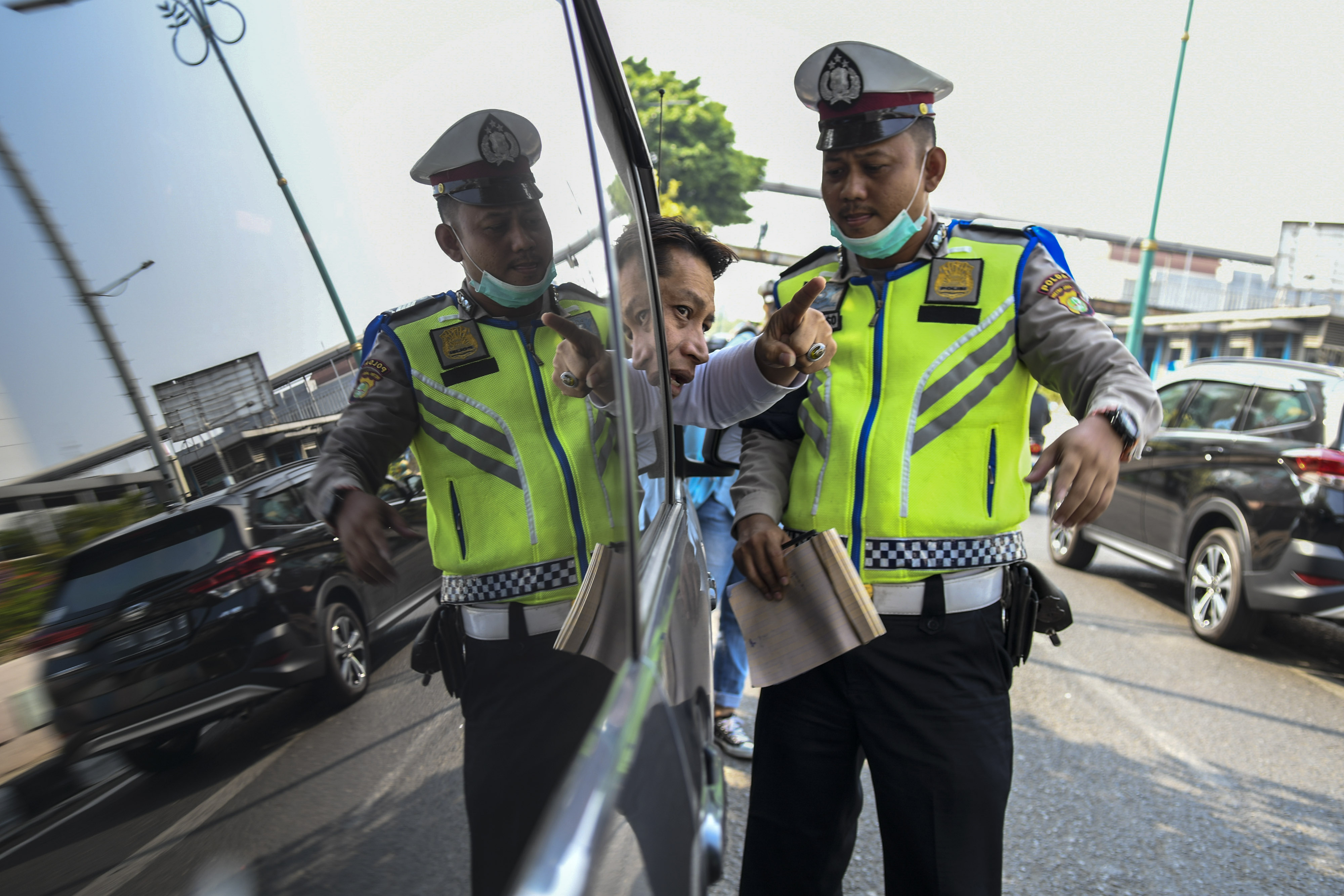 Petugas memberikan tilang kepada pengemudi yang melanggar aturan ganjil-genap