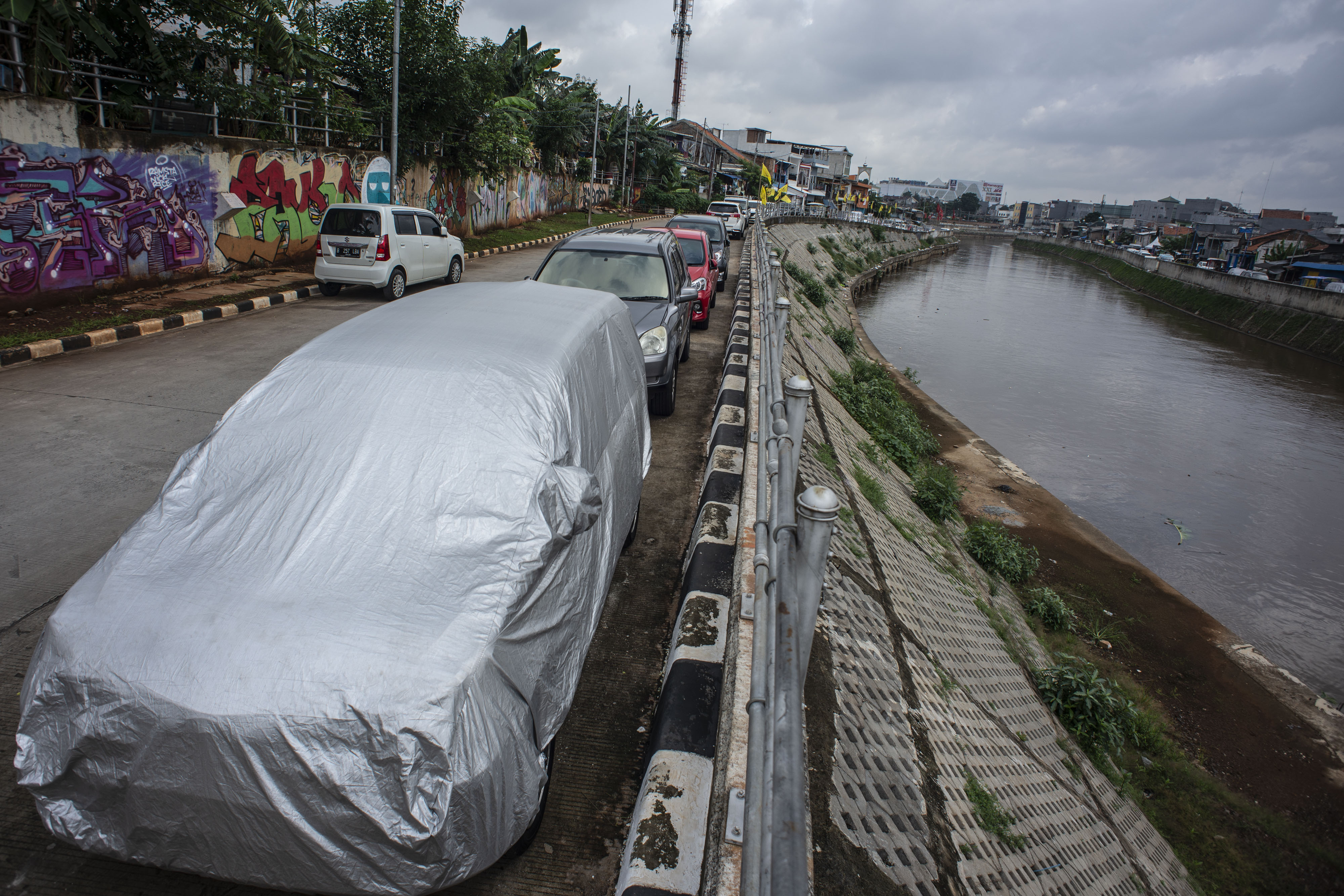 Sejumlah kendaraan terparkir di Jalan Inspeksi Sungai Ciliwung, Kampung Pulo, Jakarta, Kamis (24/1/2019).