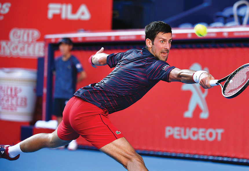 Petenis Serbia Novak Djokovic mengembalikan bola ke arah petenis Belgia David Goffi n dalam semifi nal Jepang Terbuka 2019,  