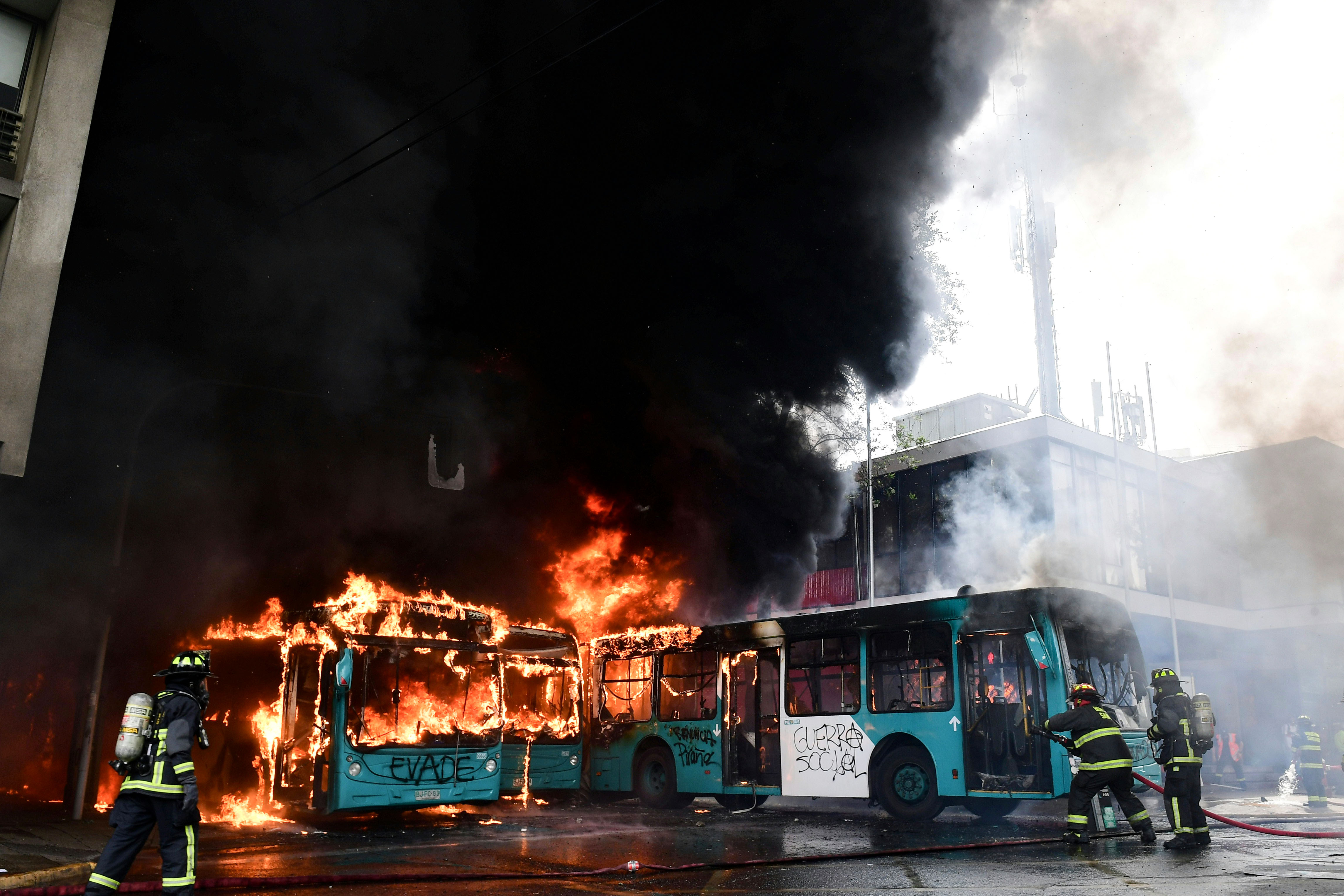 Petugas pemadam kebakaran memadamkan bus yang terbakar saat bentrokan antara pengunjuk rasa dan polisi antihuru-hara di Santiago, Cile.