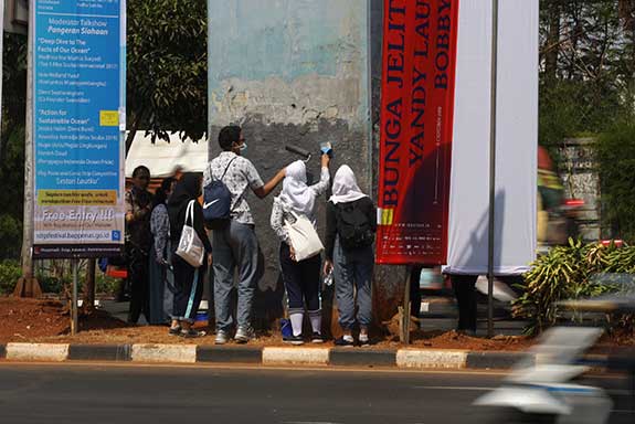 Beberapa pelajar mengecat tembok yang menjadi sasaran vandalisme saat kericuhan terjadi dalam unjuk rasa di kawasan Senayan