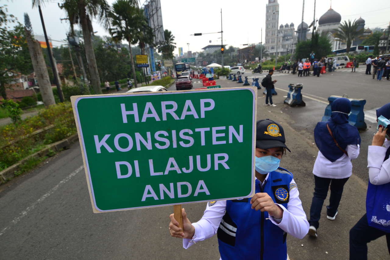 Petugas mengingatkan pengguna jalan saat saat uji coba sistem kanalisasi 2:1 di Jalur Puncak, Bogor, Jawa Barat, Minggu (27/10)