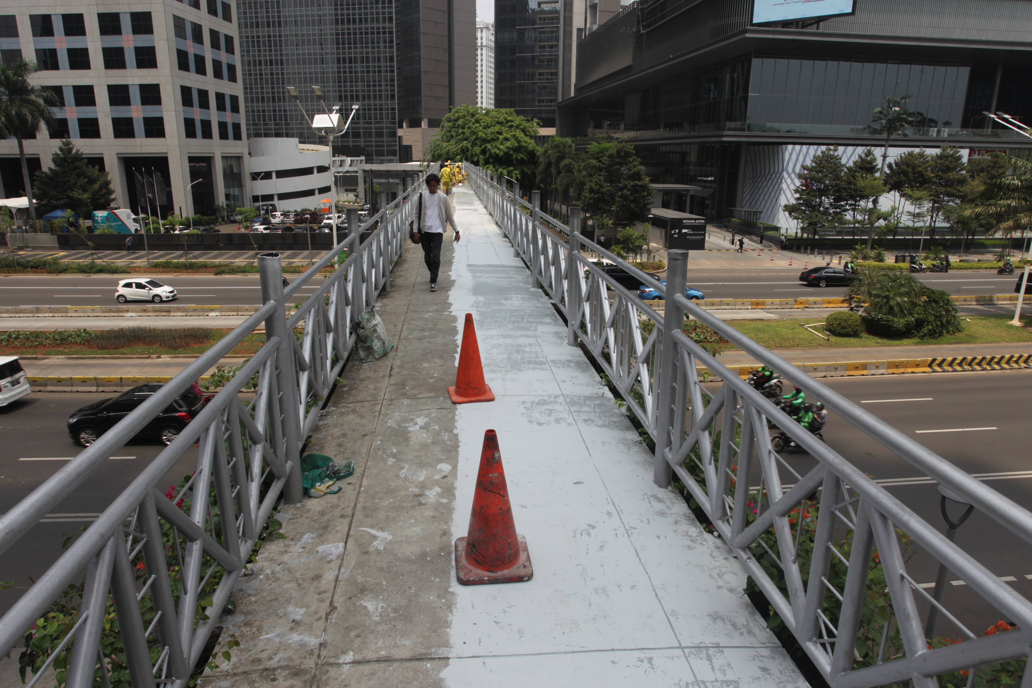 Pejalan kaki melintasi JPO tanpa atap yang terletak di antara menara Astra dan wisma Bumiputera, Jalan Sudirman
