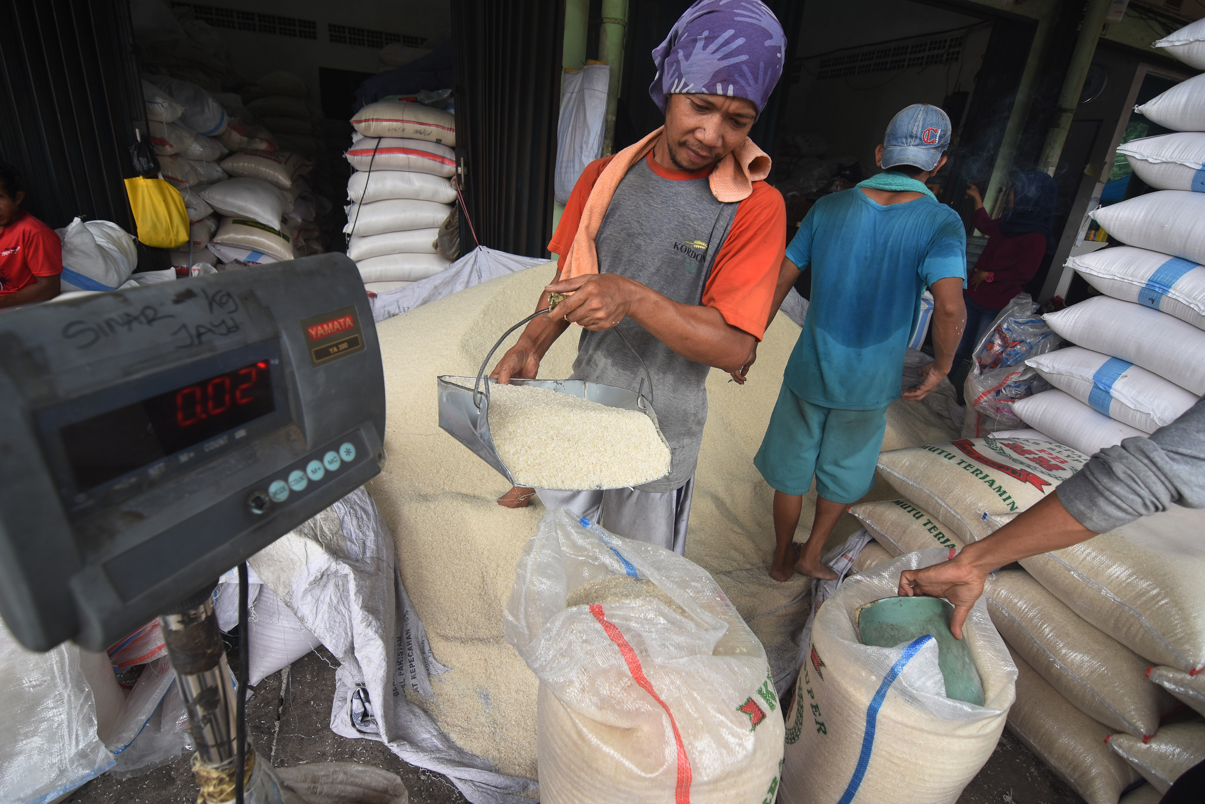 Pekerja mengemas beras ke dalam karung di Pasar Induk Beras Cipinang, Jakarta.