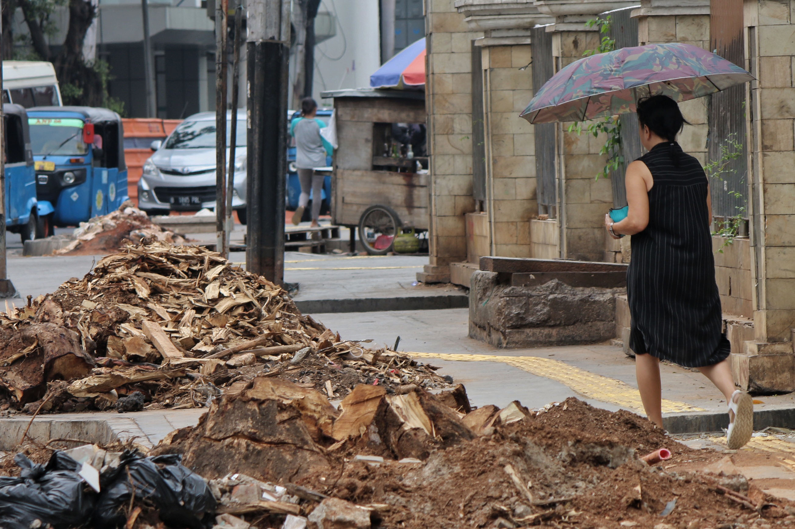Pejalan kaki melintas di pinggir tebangan pohon di Trotoar Cikini, Jalan Cikini Raya, Jakarta Pusat.