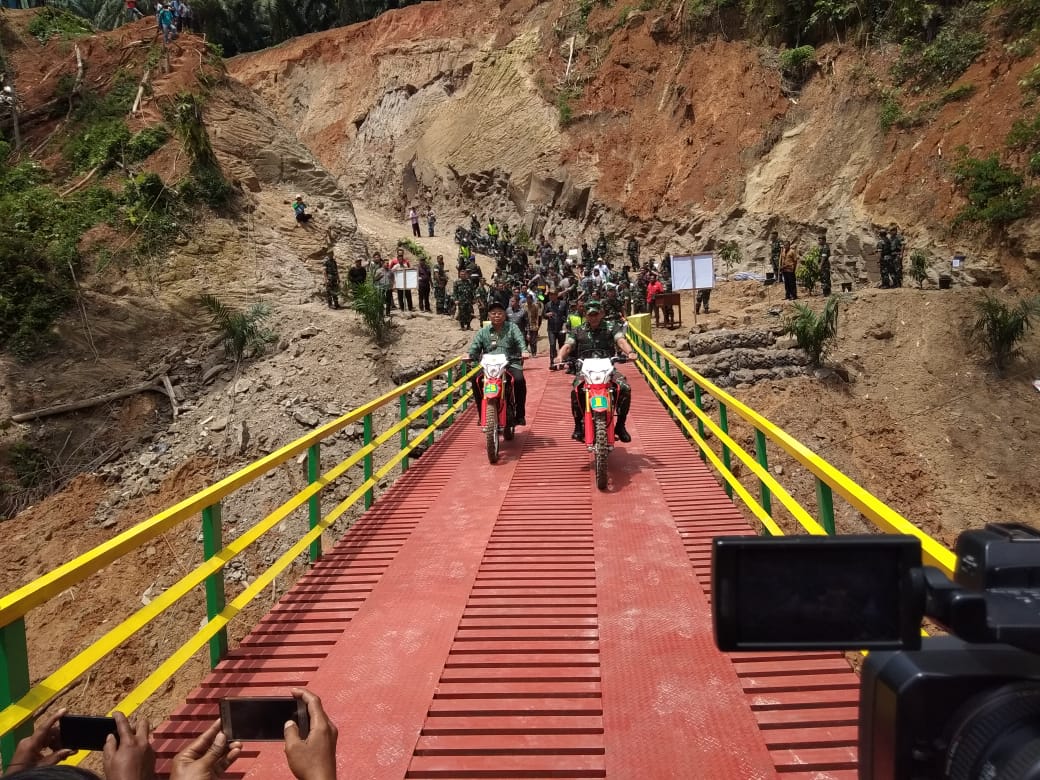 PANGDAM I/Bukit Barisan Mayjen TNI Muhamad Sabrar Fadhilah mengendari sepeda motor melintasi jembatan yang dibuat prajurit TNI dalam TMMD.