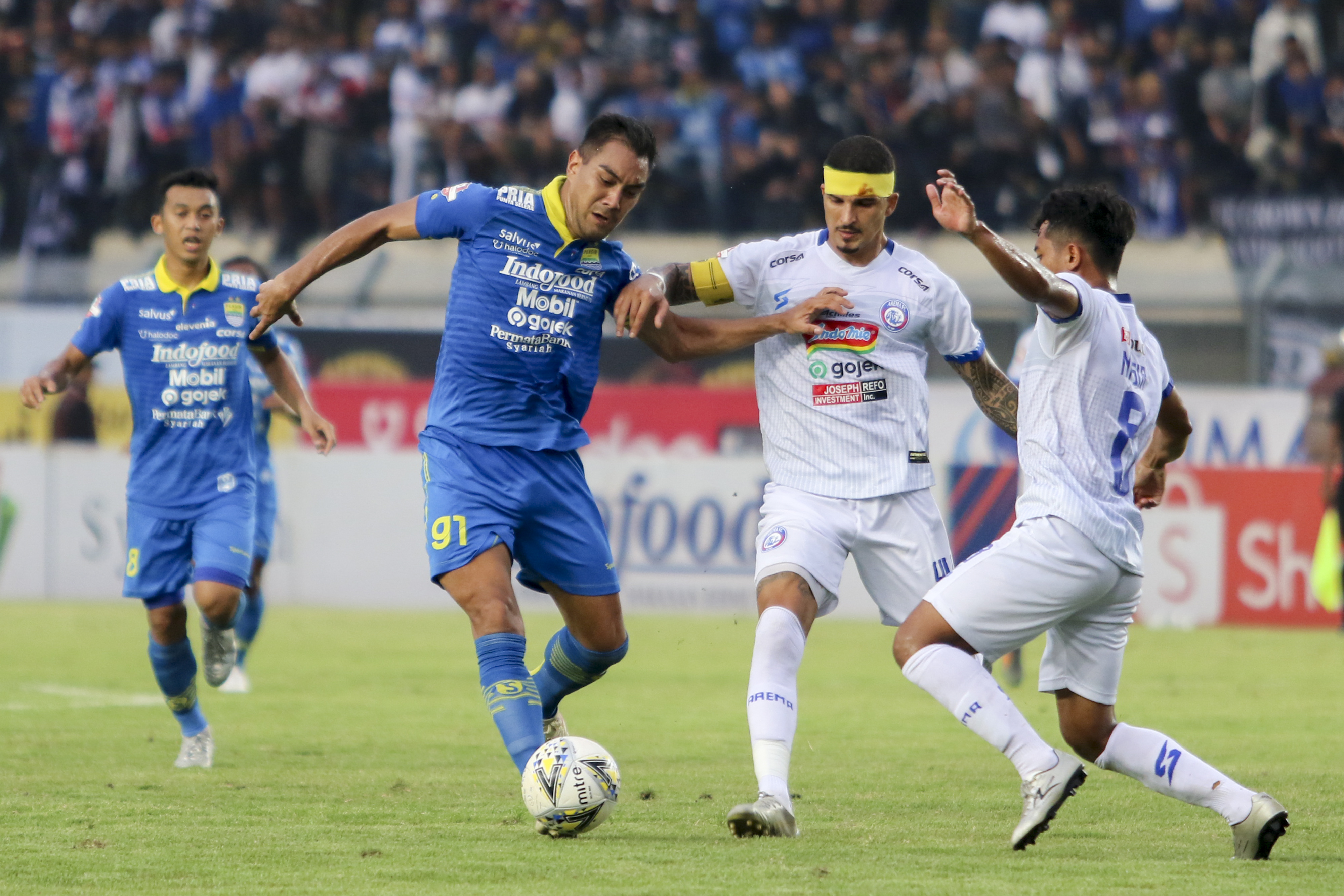 Pesepak bola Persib Bandung David Omid Nazari (kedua kiri) berebut bola dengan dua pesepak bola Arema FC Nasir (kanan) dan Arthur Rocha