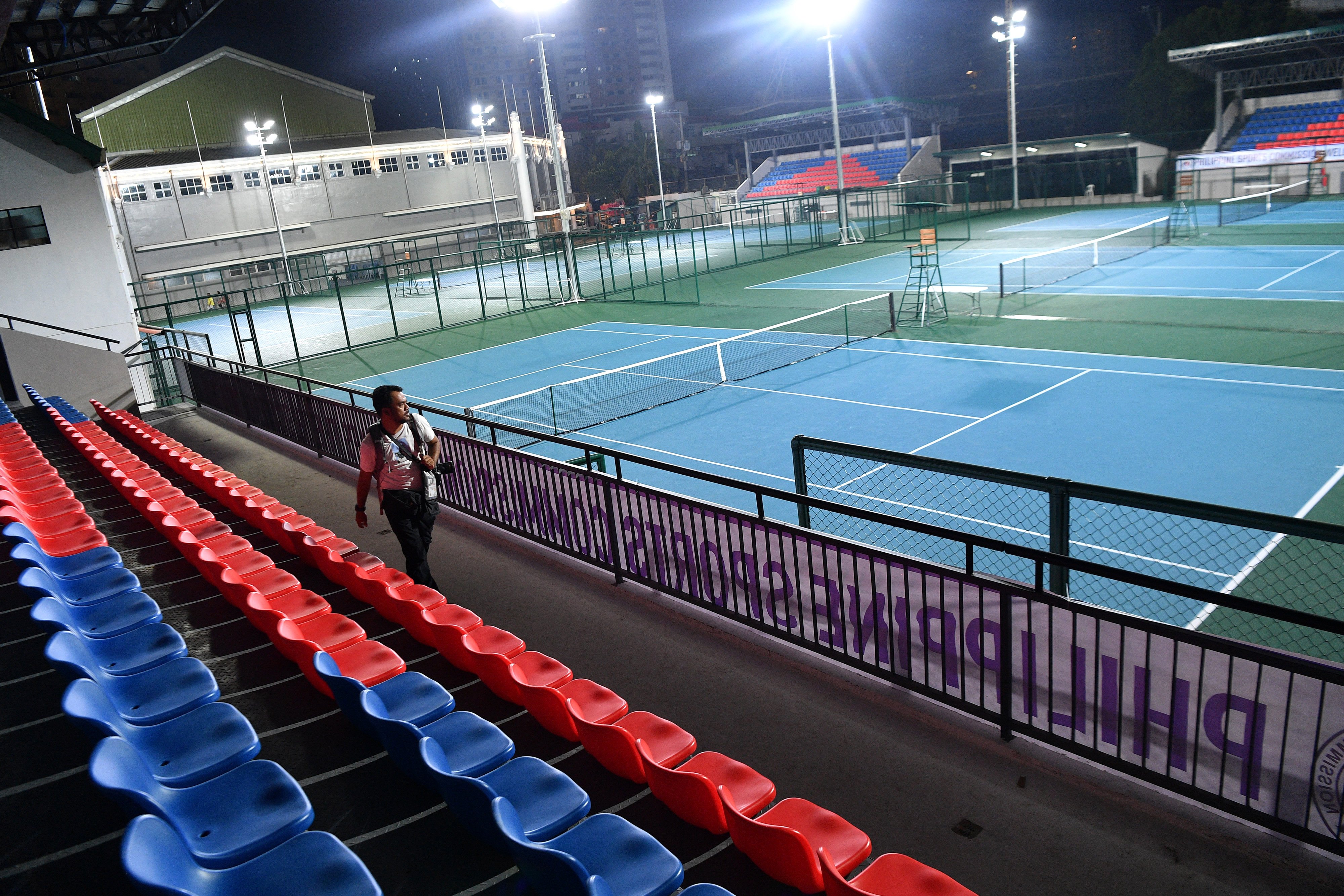 Seorang warga melintas di venue yang akan digunakan untuk cabor tenis di SEA Games 2019.