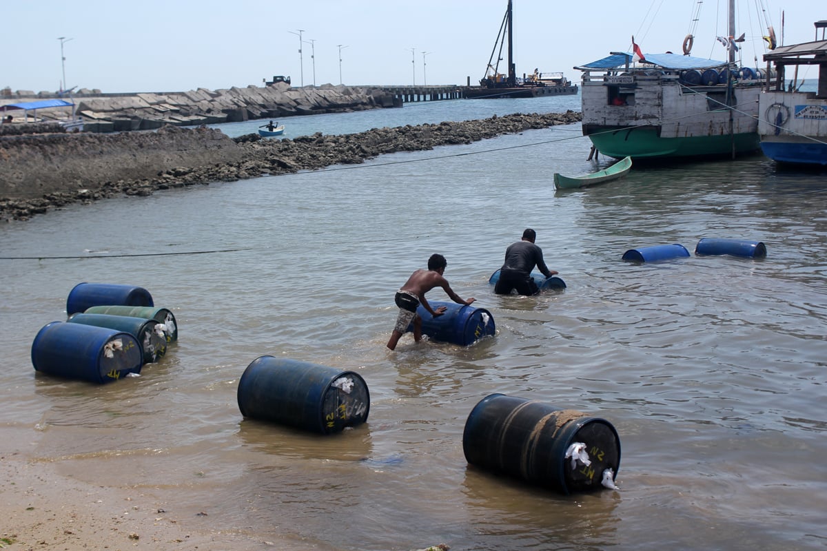 Pekerja menaikan drum berisi bahan bakar minyak (BBM) ke perahu di Pelabuhan Rakyat Namosain, Kota Kupang, Nusa Tenggara Timur (NTT)