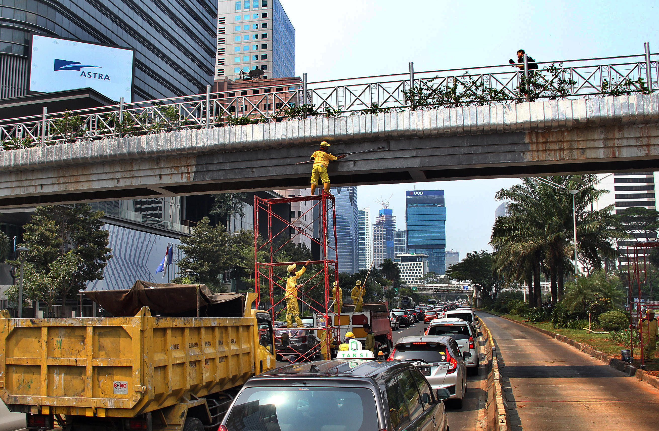 Petugas Dinas Bina Marga DKI Jakarta mengecat JPO (Jembatan Penyebrangan Orang) tidak beratap di Jalan Jendral Sudirman, Jakarta Pusat, Sabt