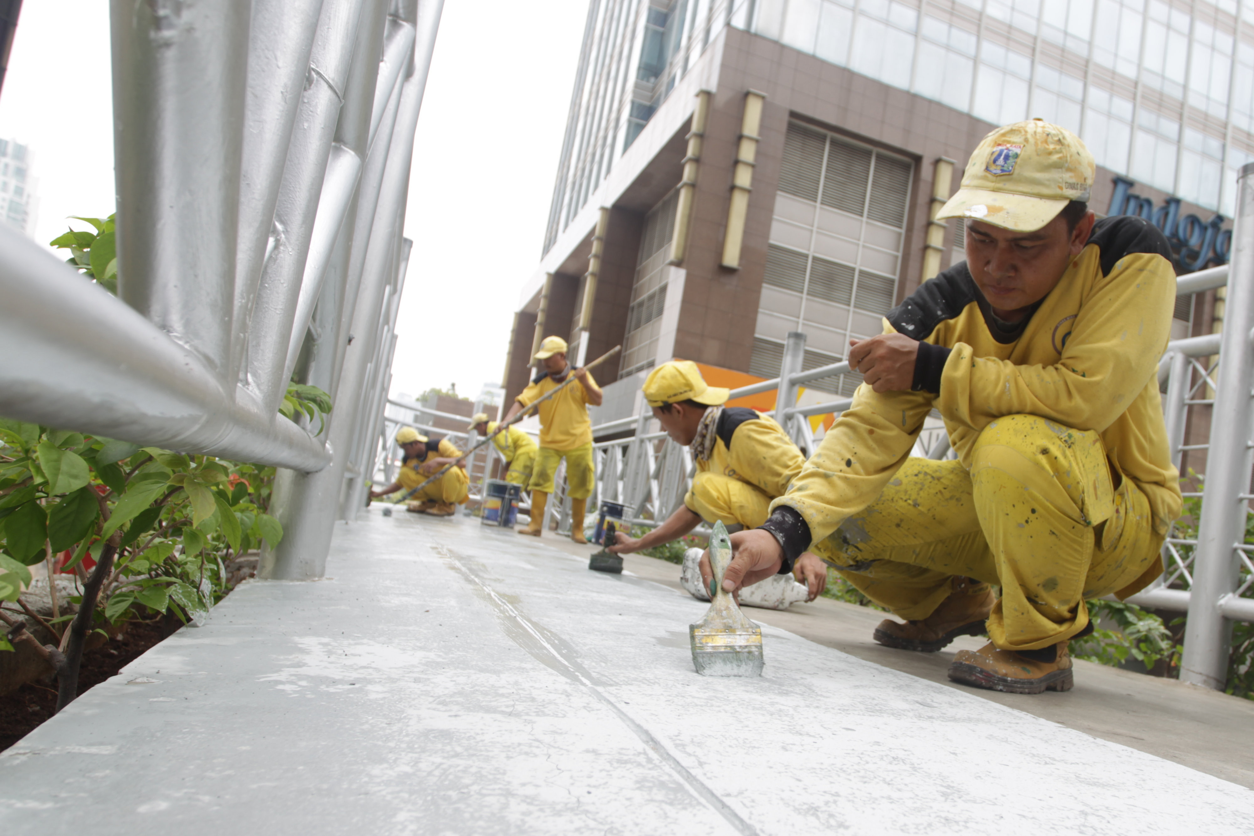 Petugas Dinas Bina Marga Pemprov DKI Jakarta melakukan pengecatan Jembatan Penyeberangan Orang (JPO) tanpa atap