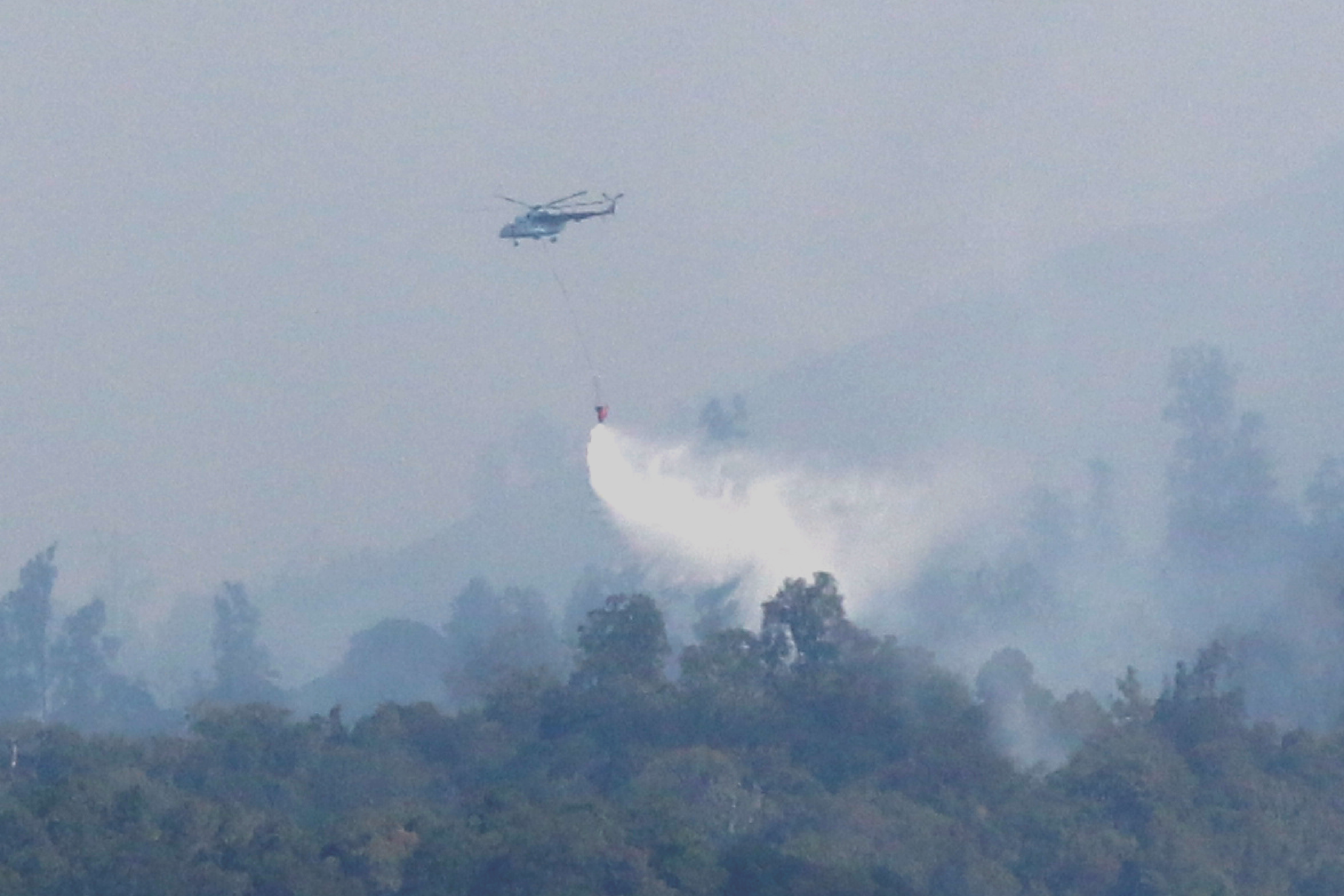 Helikopter Badan Nasional Penanggulangan Bencana (BNPB) melakukan water bombing di atas hutan yang terbakar di Cagar Alam Merapi Ungup-Ungup