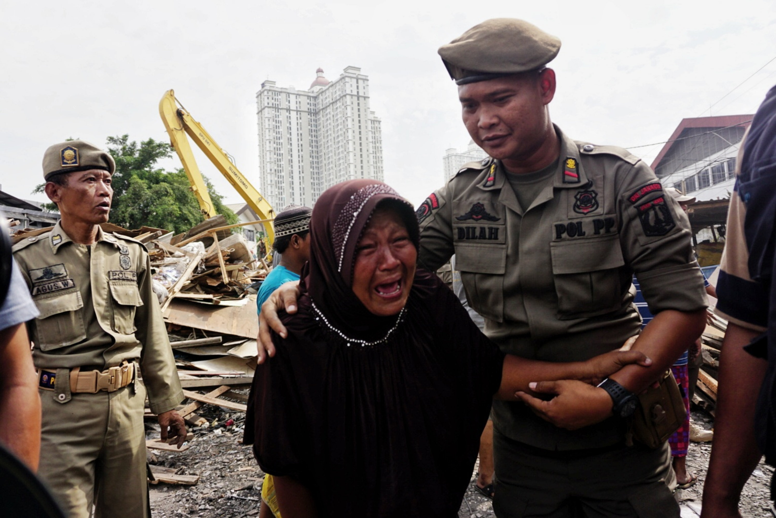 Petugas menggunakan alat berat membongkar bangunan semi permanen di pinggiran Kali Sunter