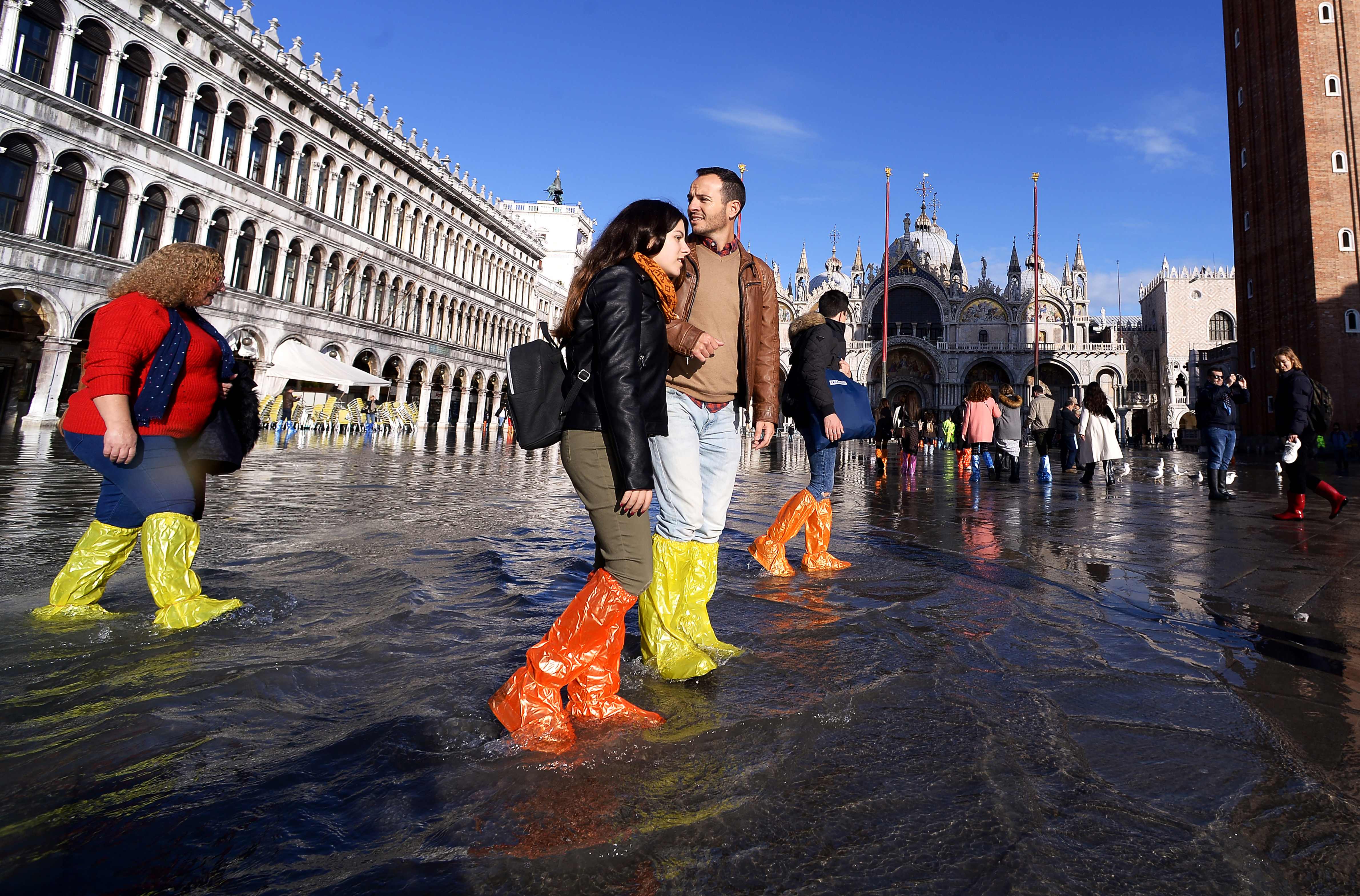 Turis mengenakan sepatu antiair berjalan di St Mark's Square, Venesia