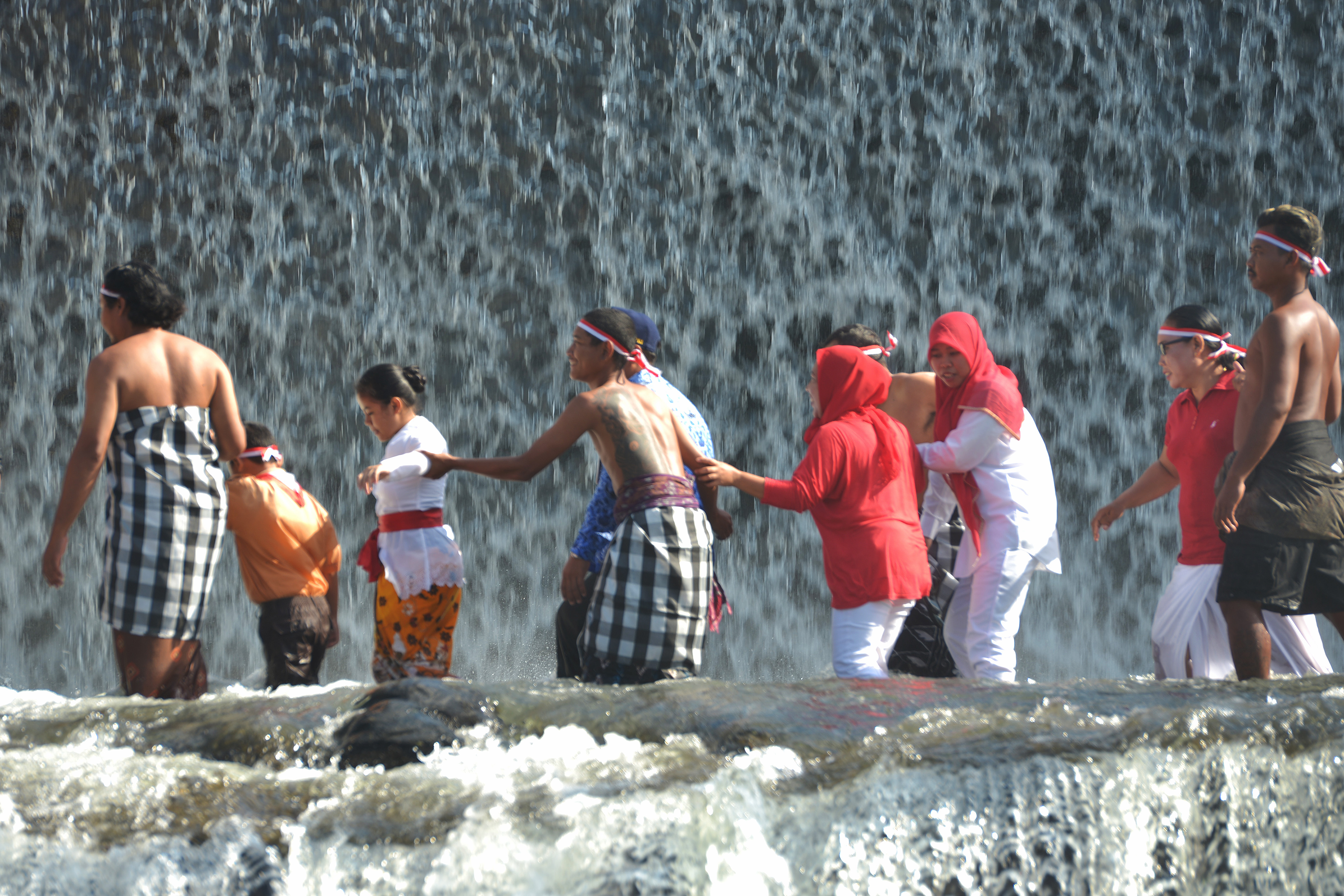 Warga Bali saat menyeberangi sungai seusai upacara HUT ke-74 Proklamasi Kemerdekaan RI di Sungai Unda, Klungkung, Bali, Sabtu (17/8/2019).