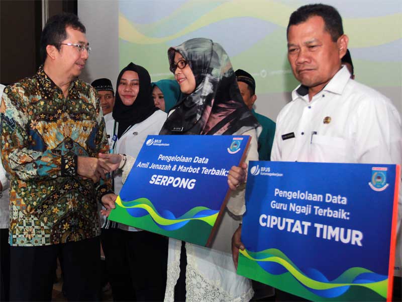 Direktur Kepesertaan BPJS Ketenagakerjaan E. Ilyas Lubis (kiri) menyerahkan kartu kepersertaan secara simbolis bagi Pekerja Rentan.