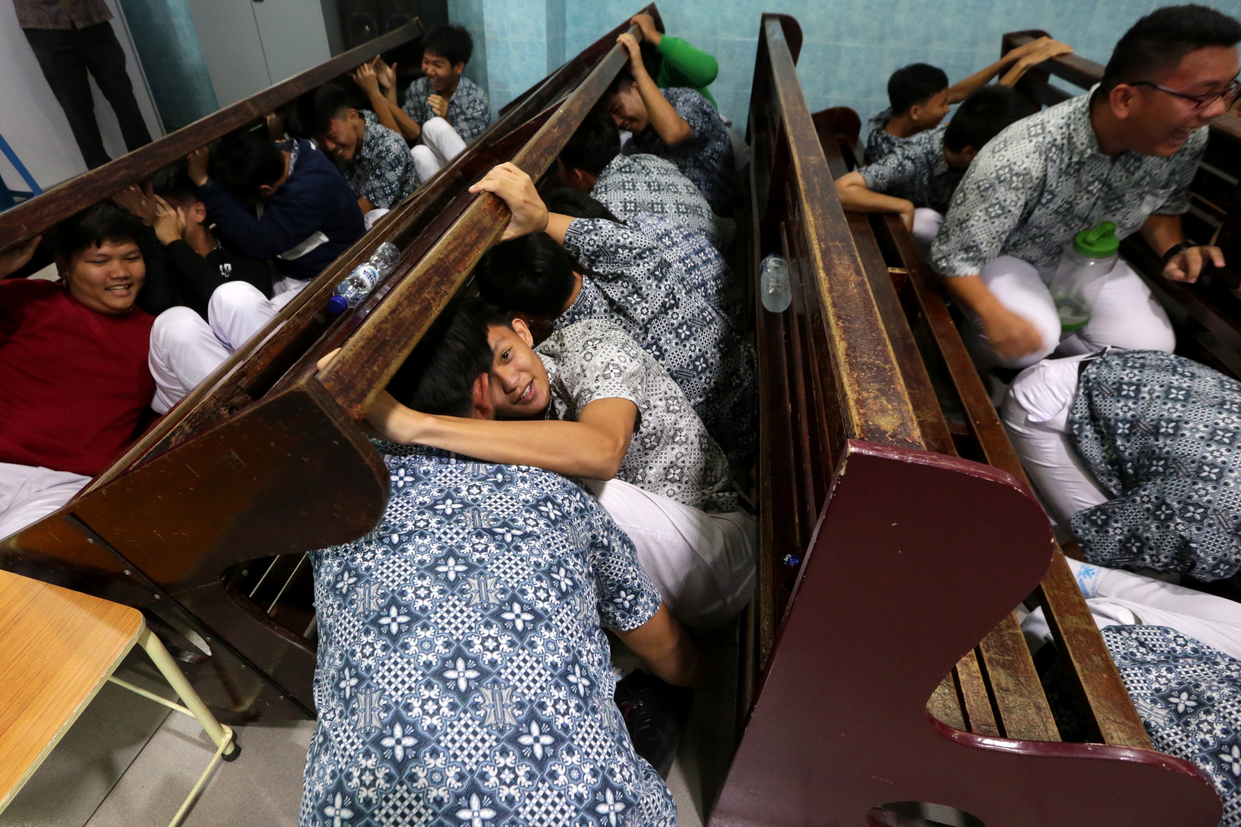 Pelajar berupaya melindungi kepala dengan kursi saat mengikuti simulasi mitigasi bencana gempa dan tsunami di SMA Methodist, Banda Aceh