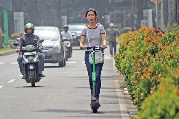 Warga menaiki skuter listrik atau otopet Grab Wheels melintas di jalan raya kawasan Senayan, Jakarta, Rabu (13/11).