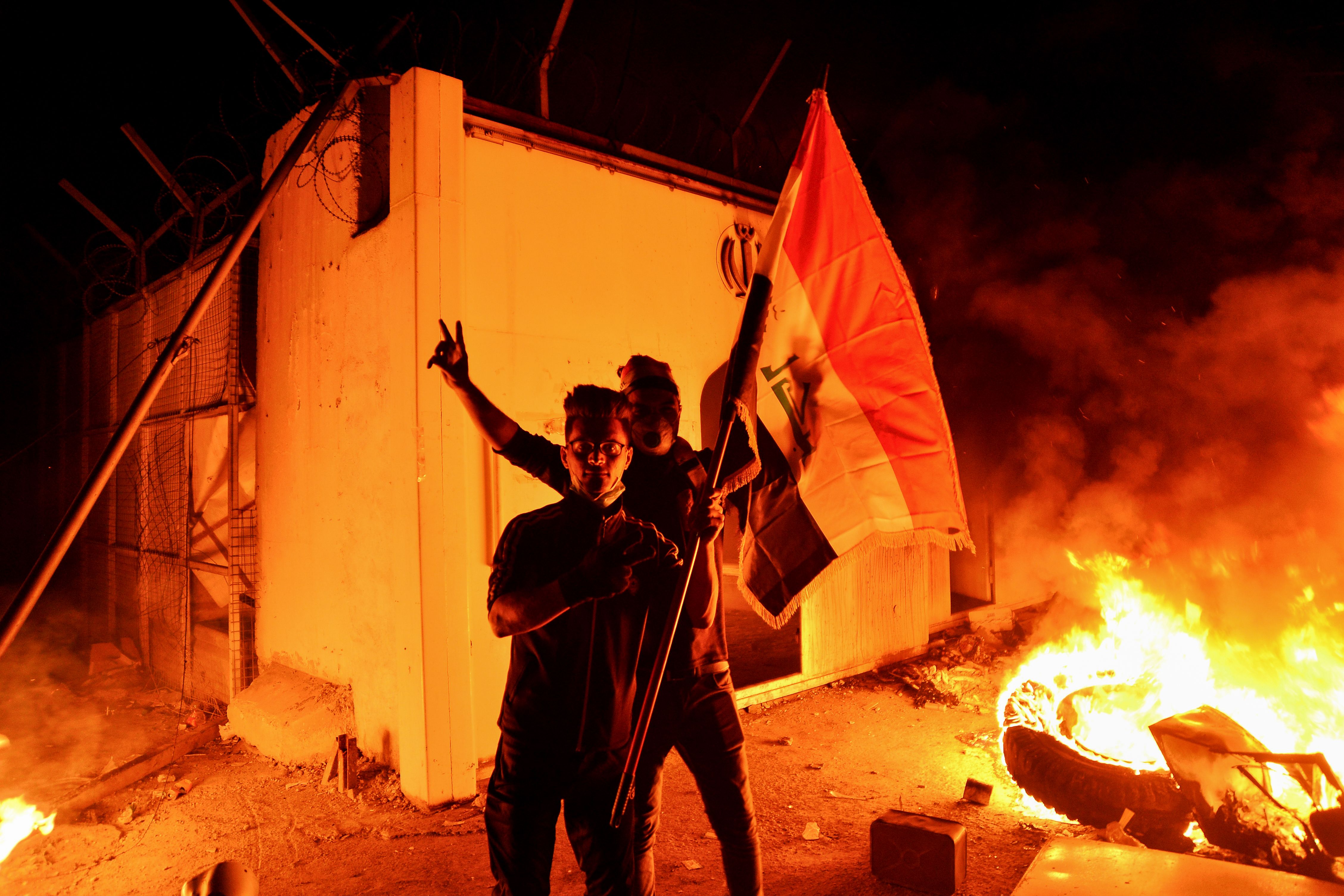 Demonstran membawa bendera Irak setelah membakar konsulat Iran di Kota Najaf.