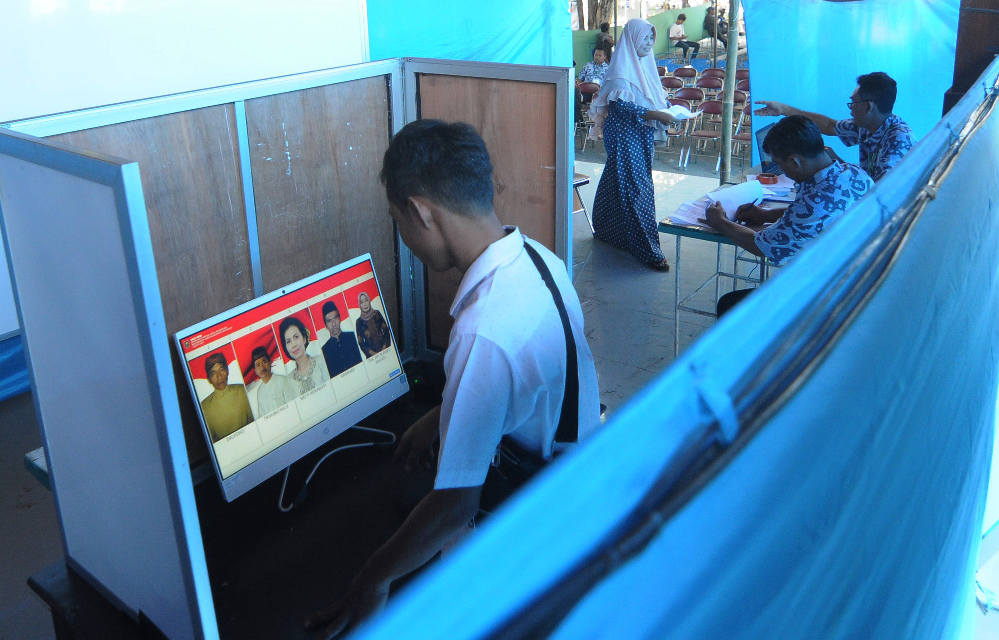 Pemilih mengamati foto calon kepala desa pada layar komputer saat melakukan Pilkades sistem e-voting di Kantor Desa Bendosari, Boyolali.